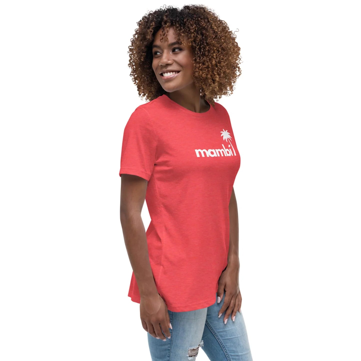 A woman with curly hair smiles in her Printful Abigail Relaxed-Fit Logo Tee—a red shirt featuring a white palm tree graphic and the word mambi—paired with light blue ripped jeans, set against a plain white background.
