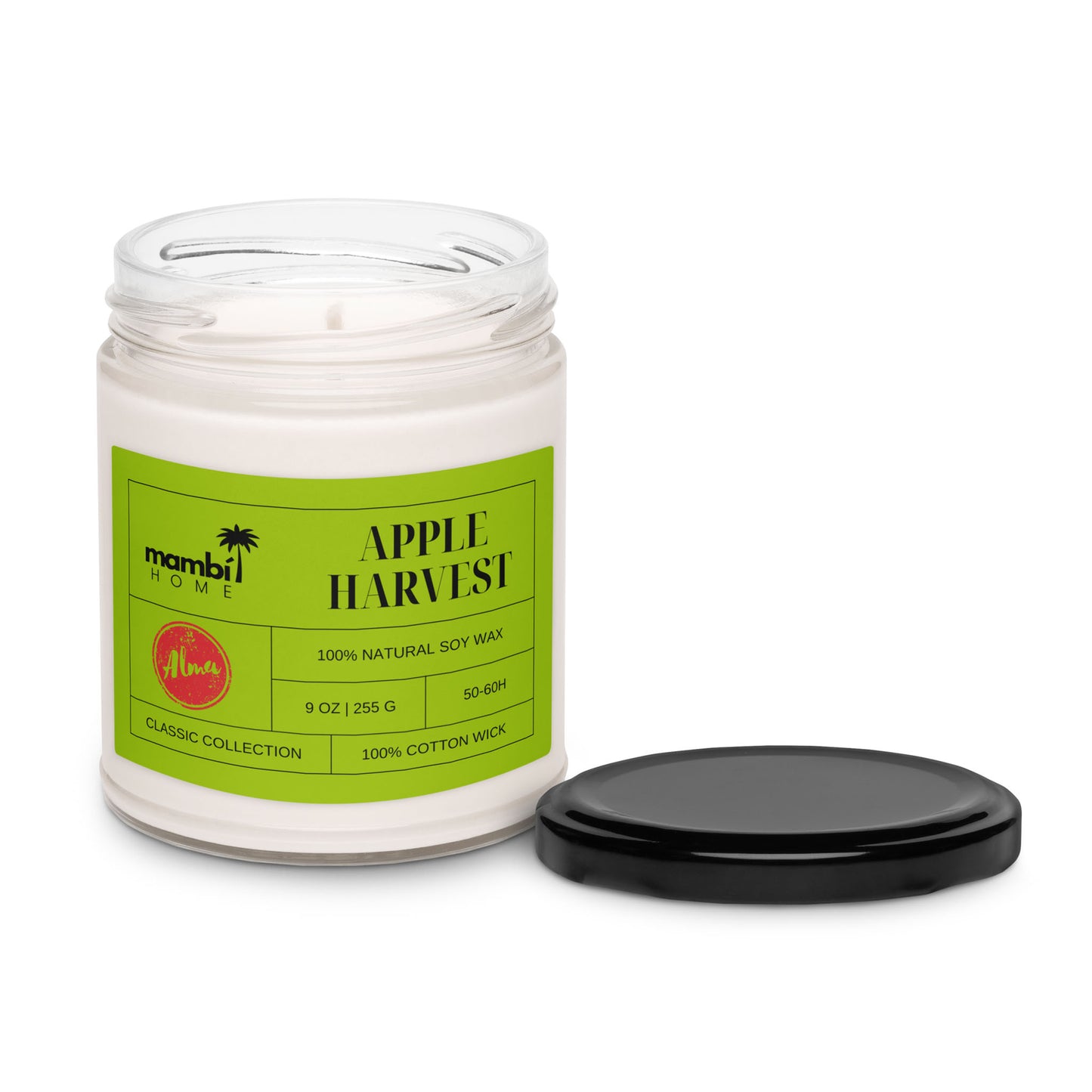 A glass jar candle labeled Apple Harvest with a green label sits next to its black lid. This scented soy candle is 100% natural soy wax, 9 oz, with a cotton wick, and part of the Classic Collection by mambi HOME.