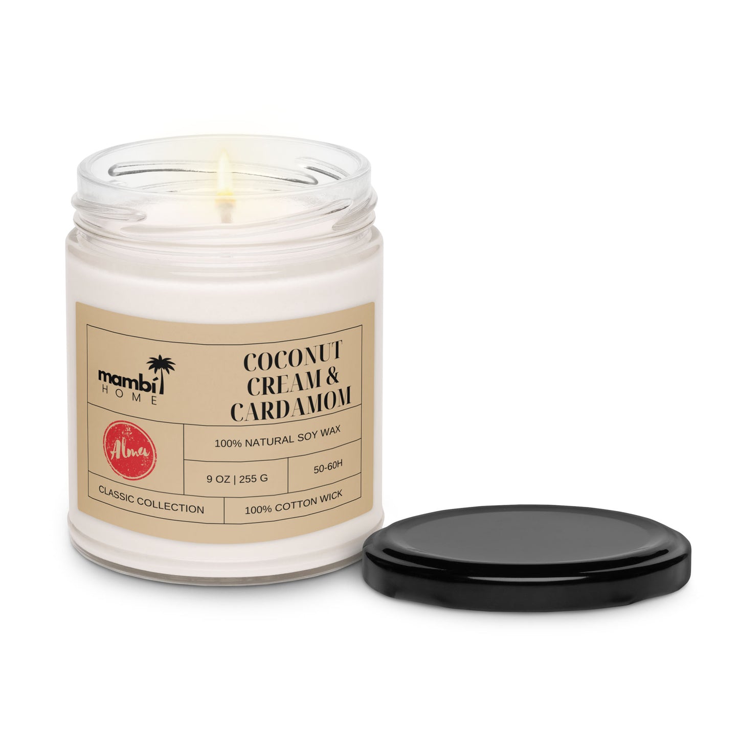 A lit coconut cream and cardamom scented soy candle in a glass jar labeled Mambi Home, with a black lid beside it. The label notes 100% natural soy wax, 9 oz, and a 100% cotton wick—perfect for those seeking eco-friendly candles.