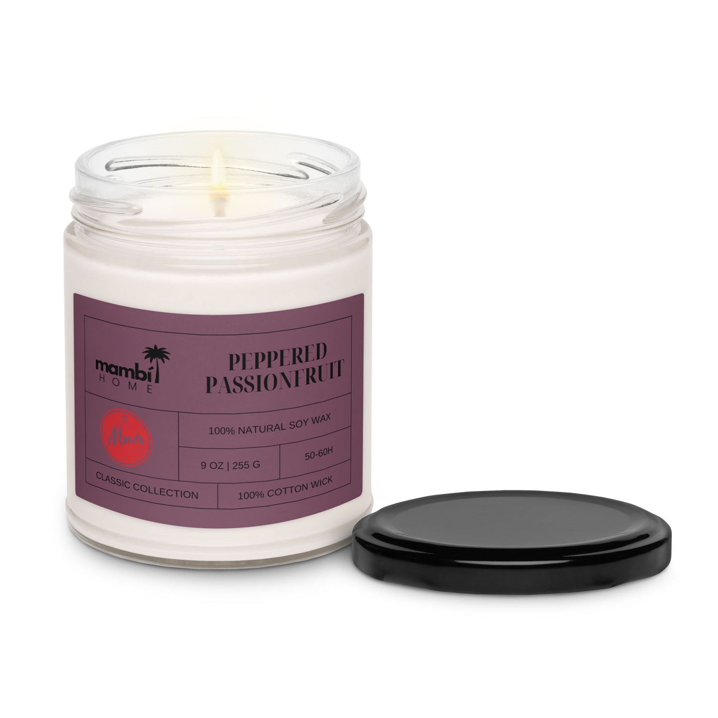 A lit eco-friendly candle in a clear glass jar labeled “Peppered Passionfruit” by mambi HOME, with a black lid beside it. This natural soy wax candle features a 100% cotton wick and comes in a 9 oz size.