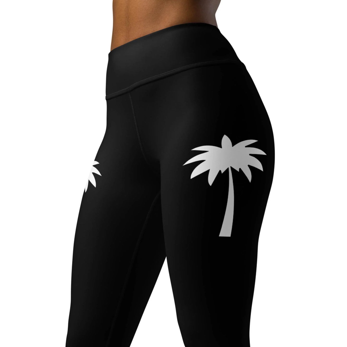 A person models Printful’s Alpine High-Rise Yoga Leggings for women, featuring a white palm tree graphic on each thigh. The image is cropped from waist to mid-thigh, showcasing an athleisure vibe.
