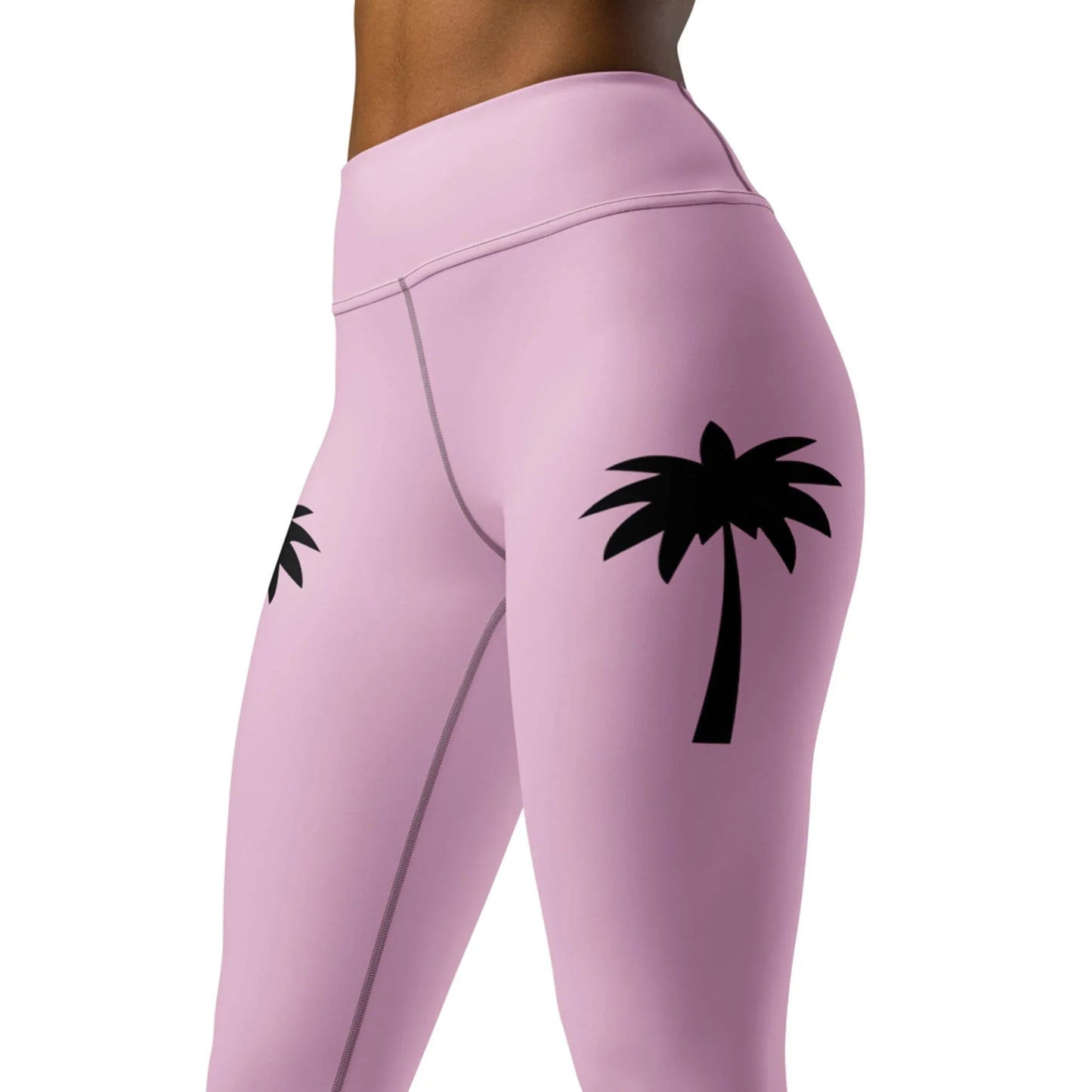 Model wears Printfuls Alpine High-Rise Yoga Leggings for women in pink, featuring black palm tree graphics on each thigh, styled between waist and mid-thigh for a trendy athleisure look.