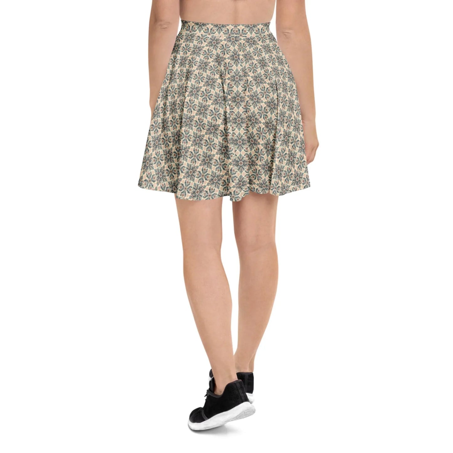 A person stands facing away, wearing a high-waisted, flared Mambí skirt with a blue and beige floral pattern. They pair it with black sneakers and a cropped top, shown from the waist down.