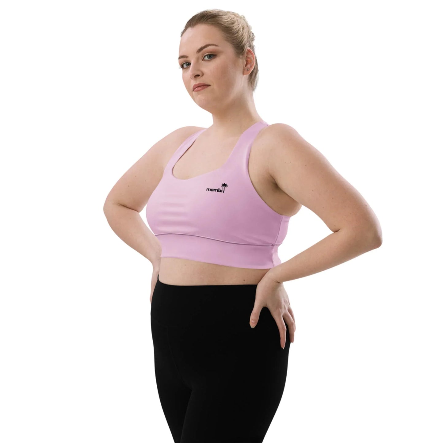 A woman stands confidently with hands on hips, wearing the Printful Ashley Longline Sports Bra for women in light purple, made from recycled polyester, paired with black leggings against a plain white background.