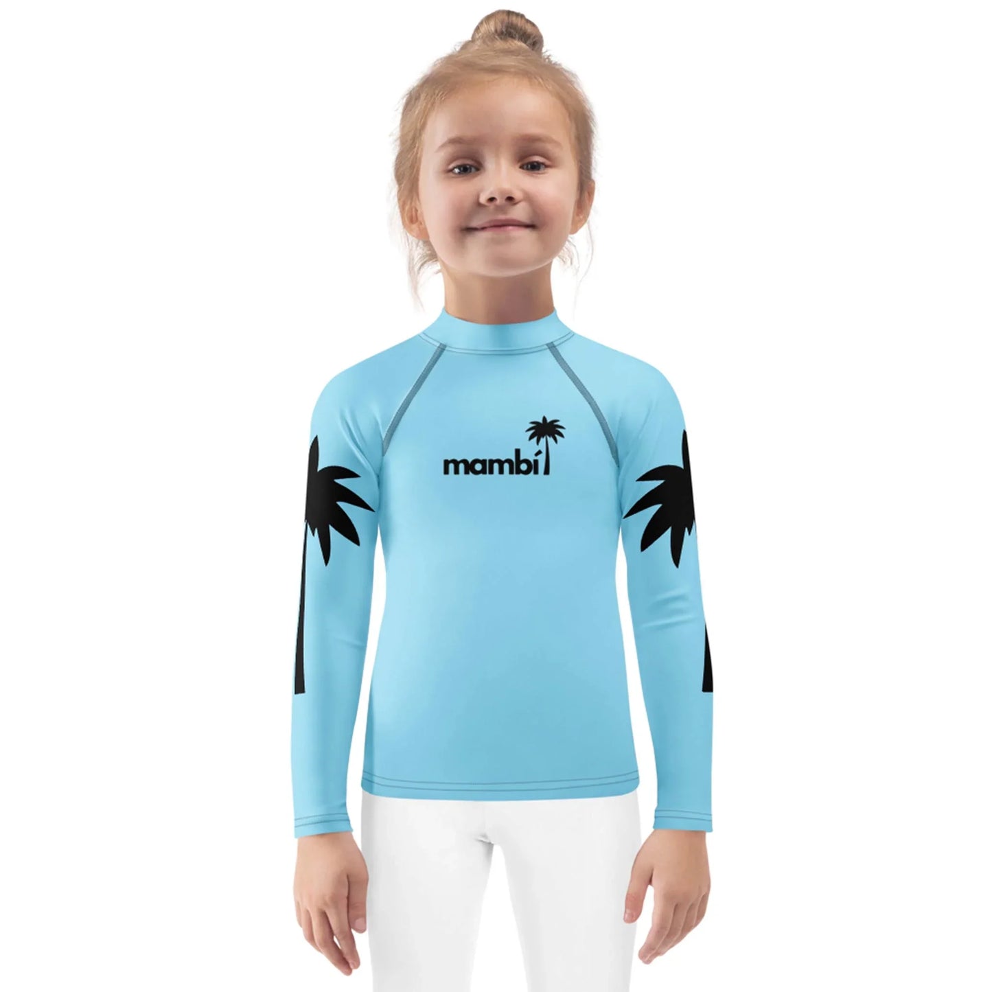 A young girl with blonde hair in a bun wears a light blue long-sleeve Mambí rash guard with black palm tree graphics on the sleeves and a palm tree logo on the chest, standing against a white background.