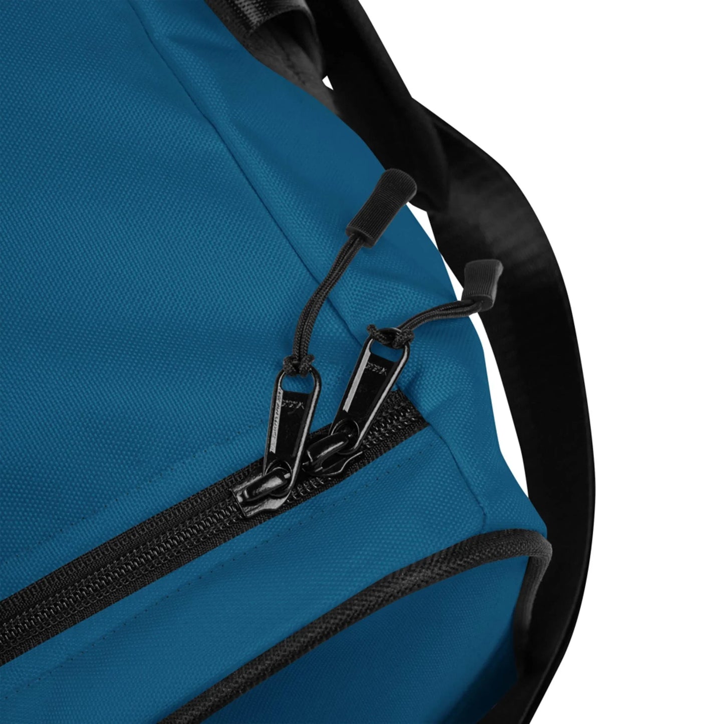 Close-up of a blue Mambí fabric bag with a black zipper and two zipper pulls. A black strap is partially visible on the right side of the image.