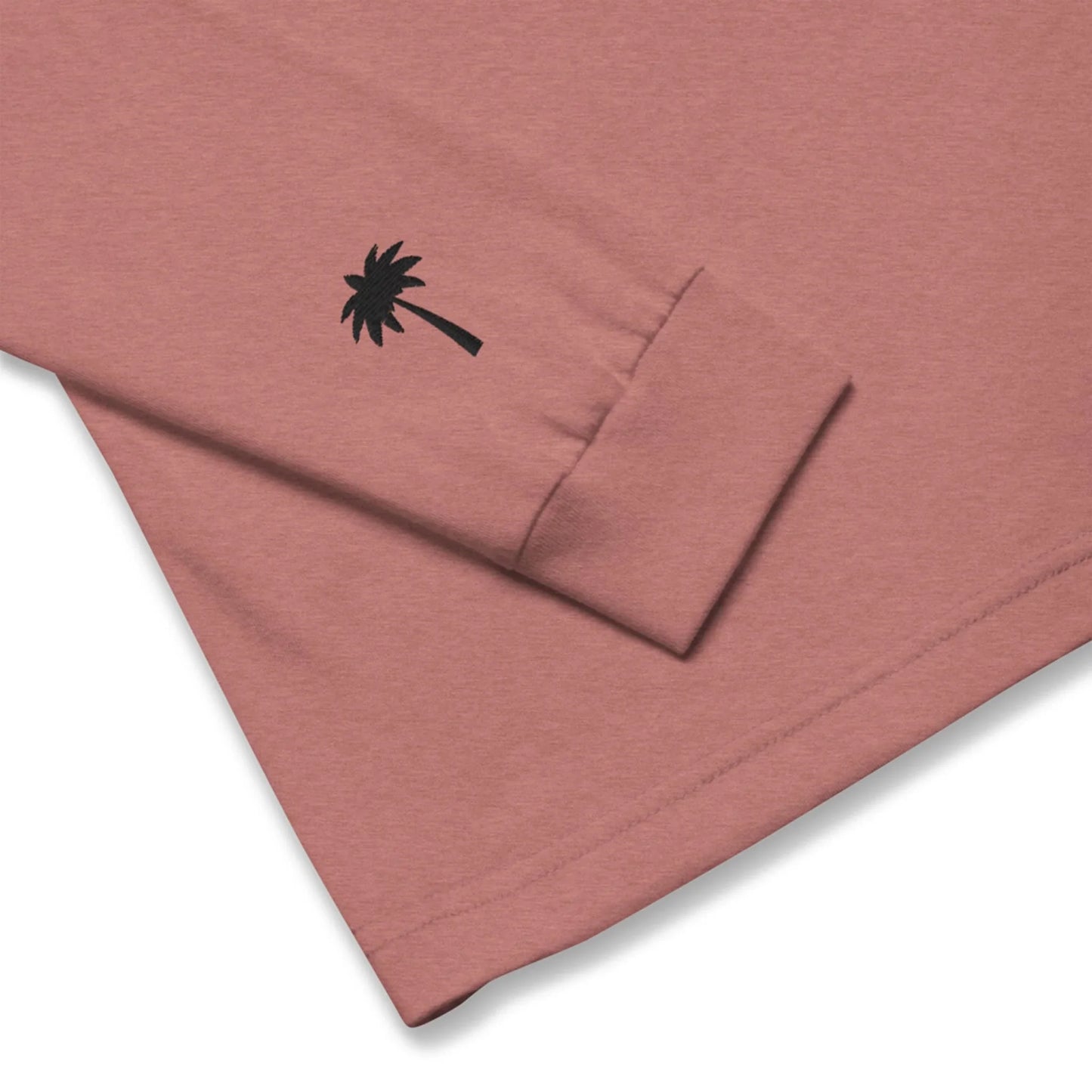 A close-up of a mauve Mambí long-sleeve shirt featuring a black palm tree graphic near the sleeve cuff.