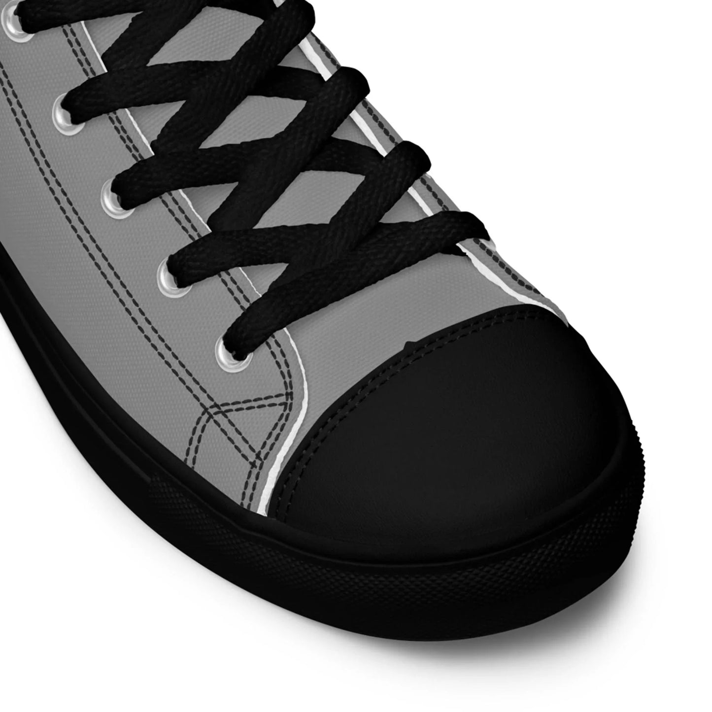 Close-up of a gray Mambí sneaker with black laces, black rubber toe cap, and black sole, highlighting the shoe’s detailed stitching and eyelets.