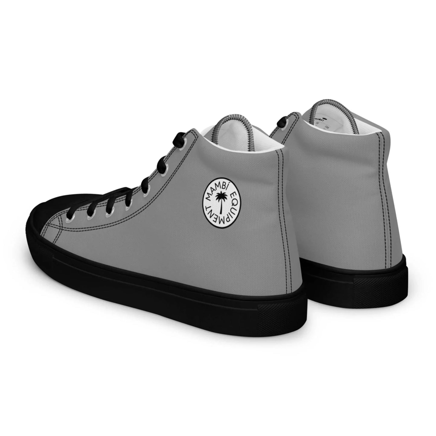 A pair of high-top Mambí sneakers with gray sides, black soles, black toe caps, and black laces. Each shoe features a circular white logo with a palm tree and the words Mambac Company on the side.