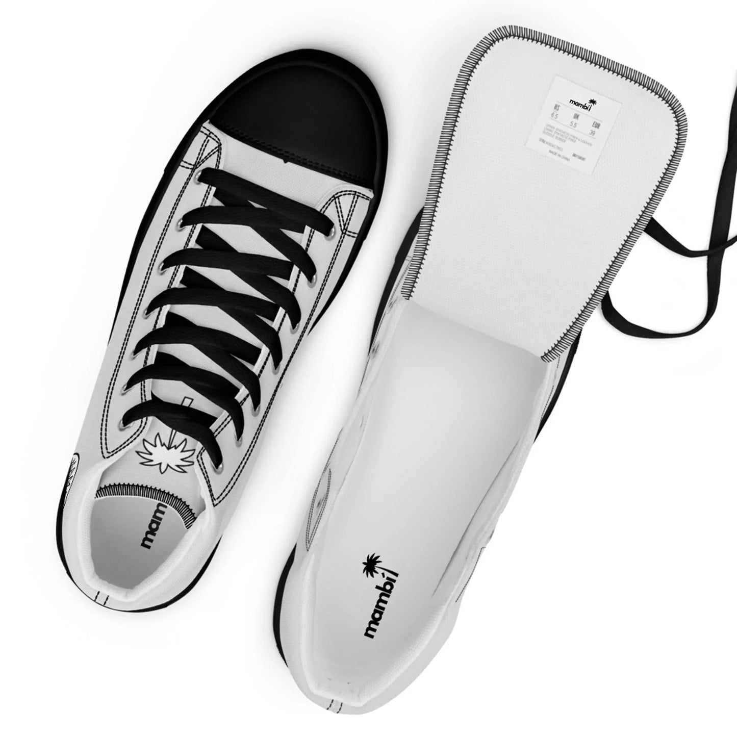 Two white Mambí sneakers with black accents are shown. One shoe is upright with black laces and a palm tree logo on the tongue; the other is opened to reveal the insole and a label inside the tongue.
