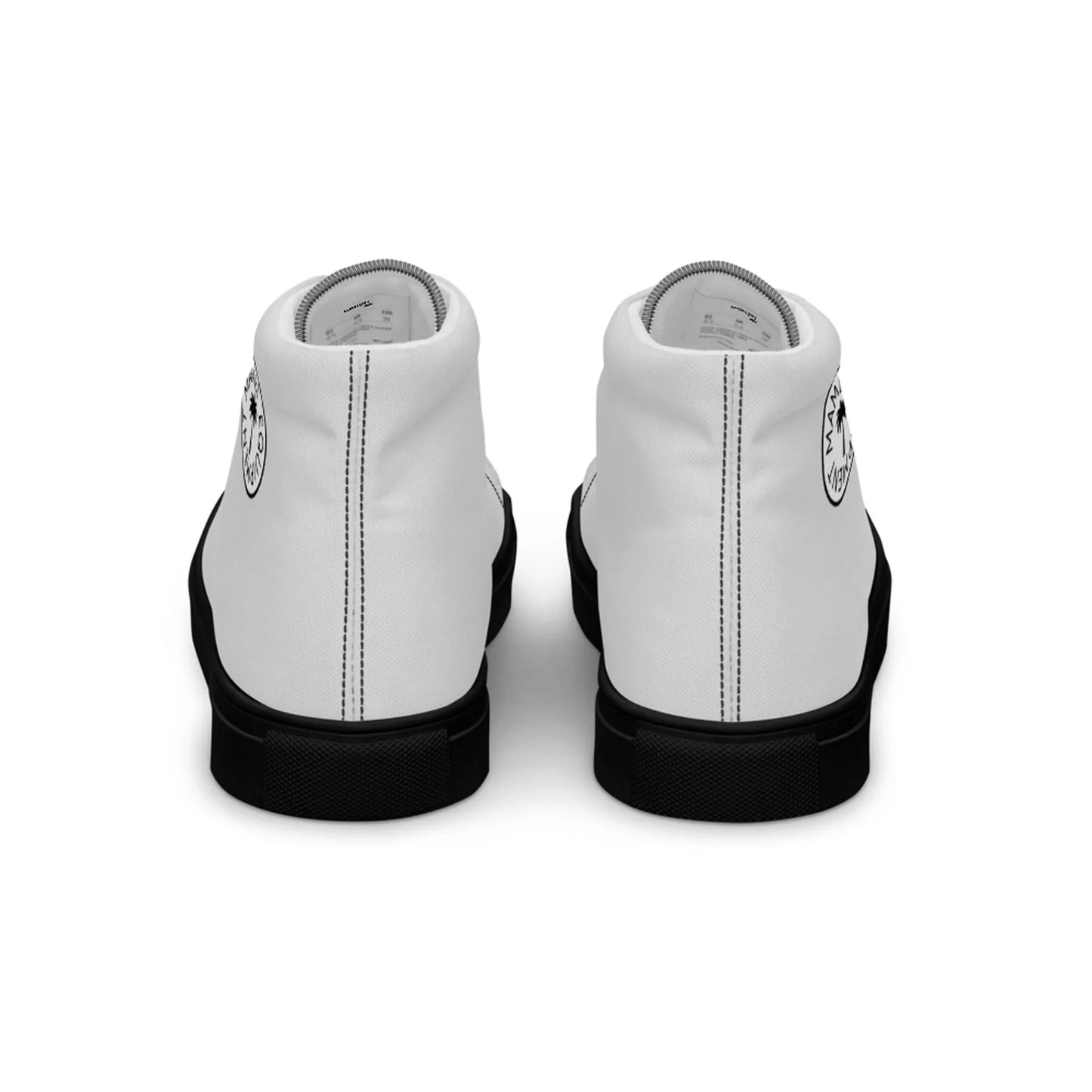 A pair of white Mambí high-top sneakers viewed from the back, featuring black soles and a circular black-and-white logo on each heel.