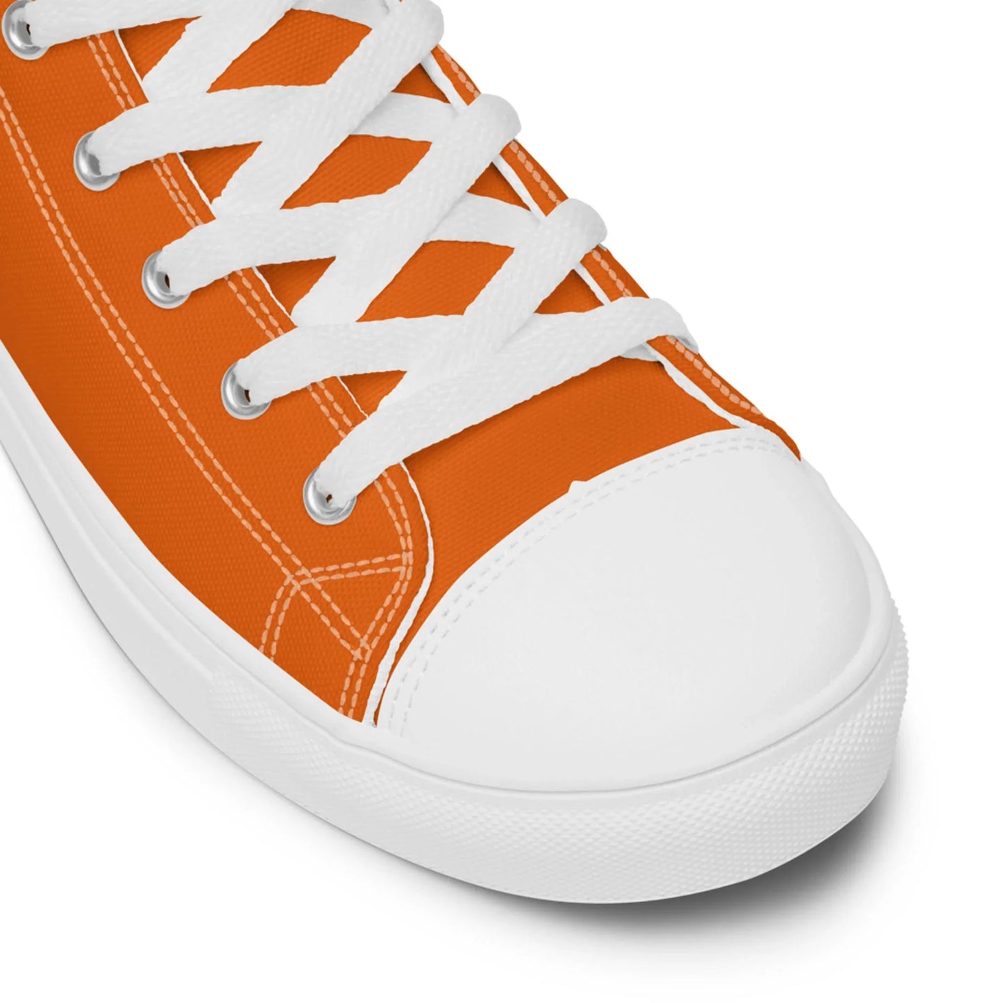 Close-up of an orange Mambí canvas sneaker with white laces, detailed stitching, and a white rubber toe cap and sole against a white background.