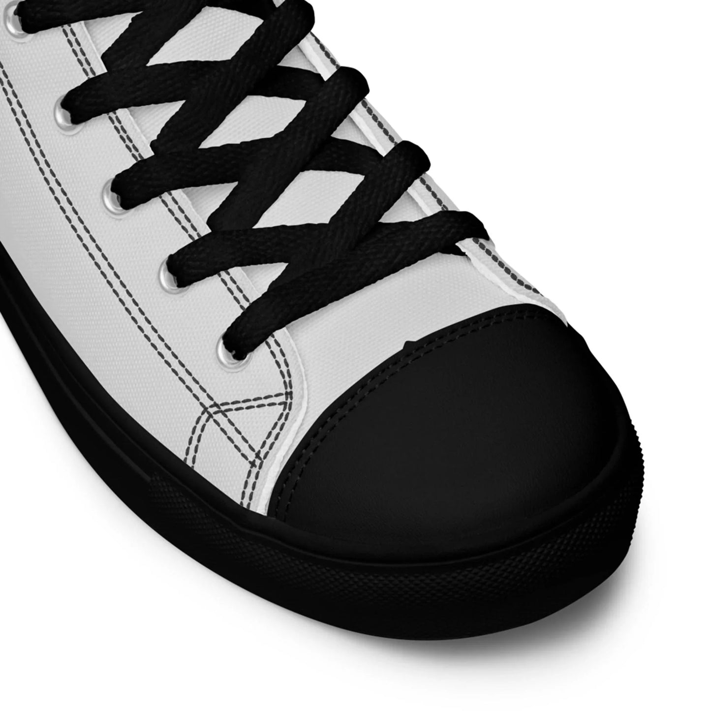Close-up of a white Mambí sneaker with black laces, black stitching, and a solid black toe cap and sole. Only the front part of the shoe is visible against a white background.
