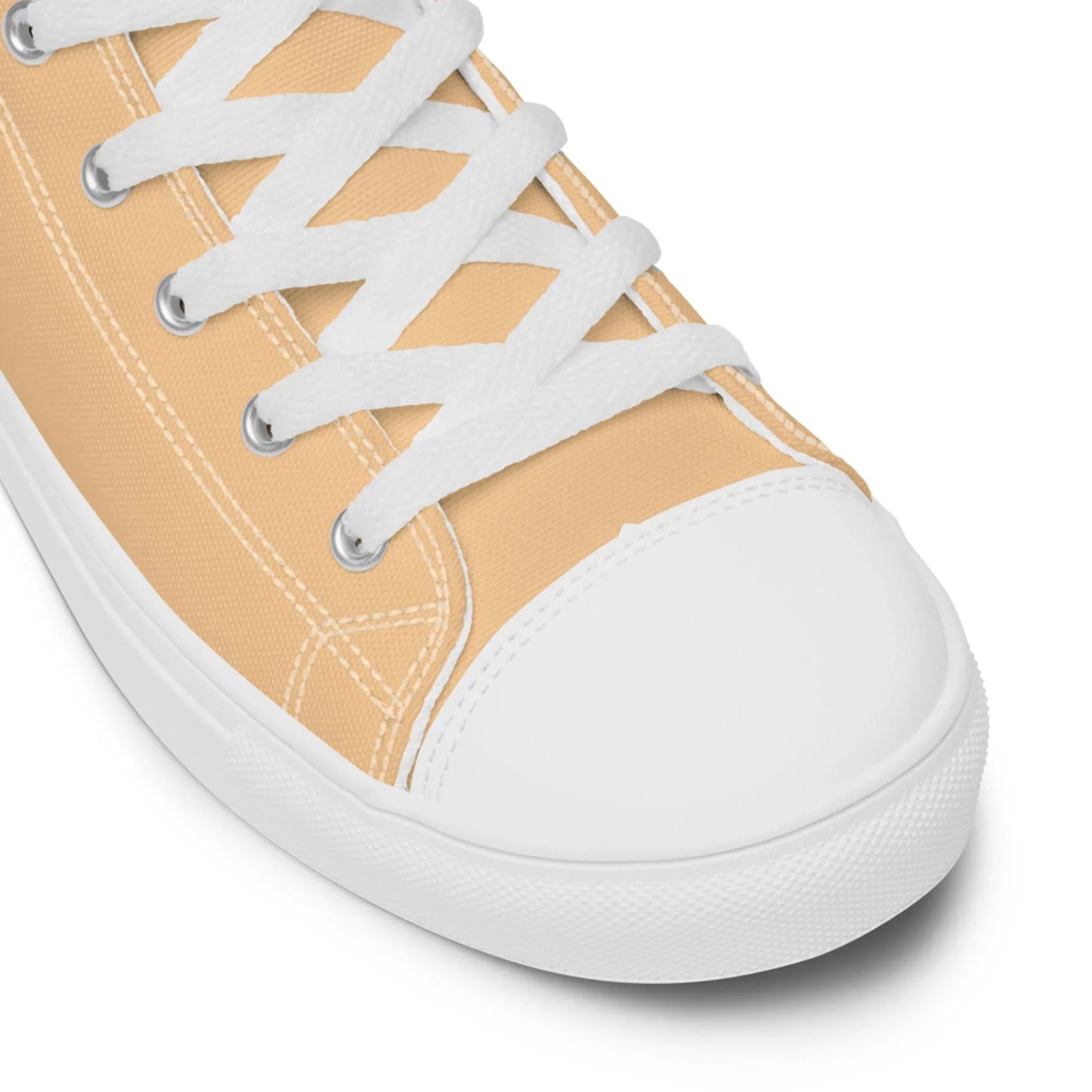Close-up of a beige Mambí canvas sneaker with white laces, a white rubber toe cap, and white stitching, shown against a plain white background.