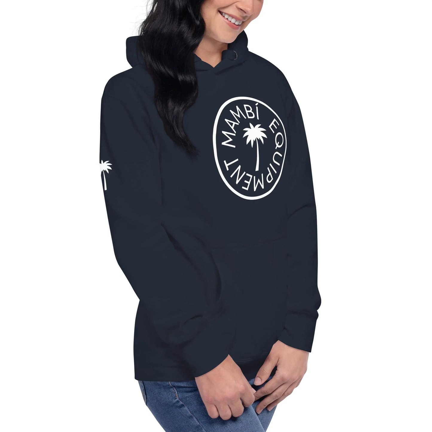 Woman wearing a navy blue Mambí hoodie with a white Mambí Equipment logo and palm tree graphic on the chest, plus a small palm tree on the sleeve, standing and smiling with hands clasped.