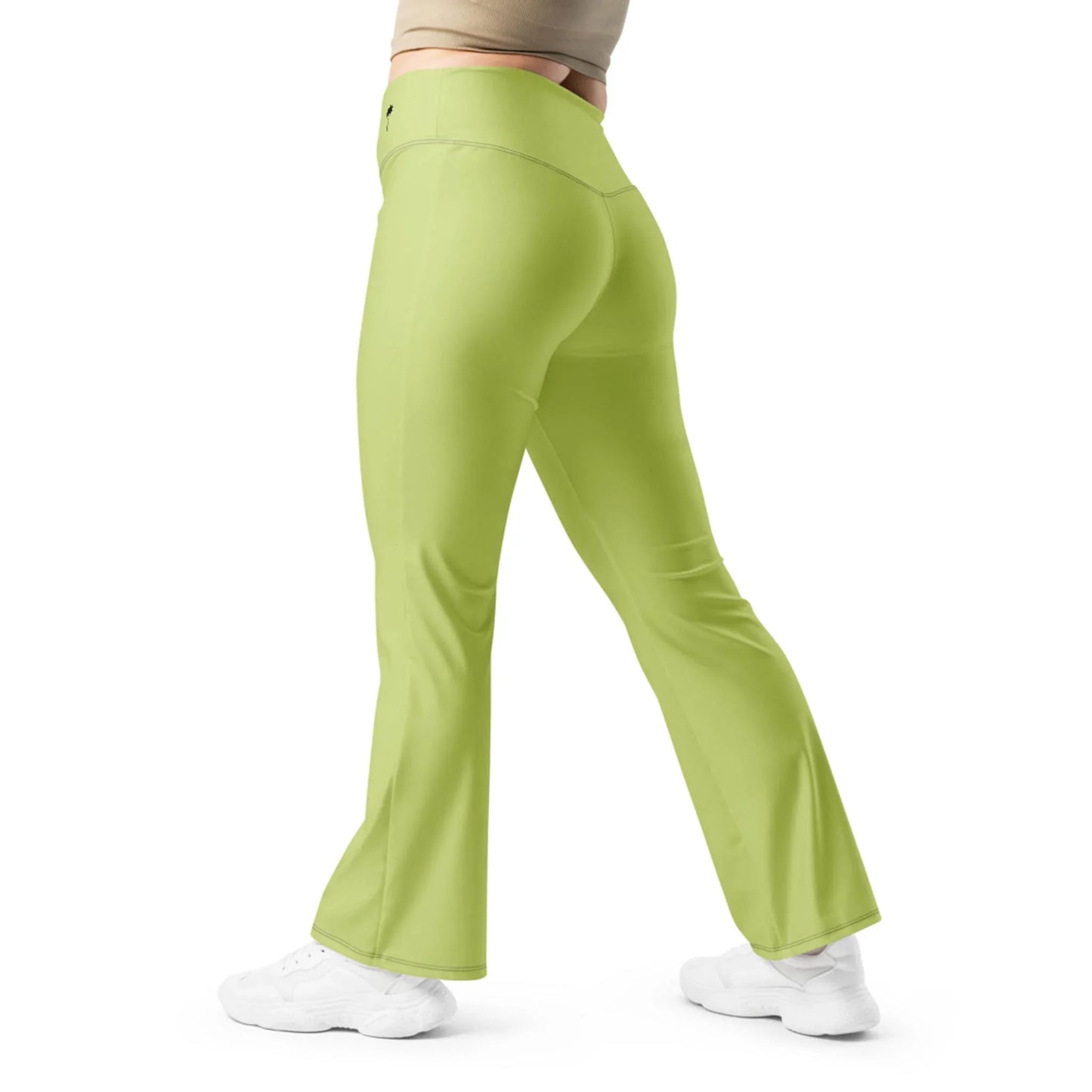 A person is shown from the side and back, standing with one leg forward, wearing Printfuls Carolina Flared Performance Leggings in high-waist light green and white sneakers against a plain white background.