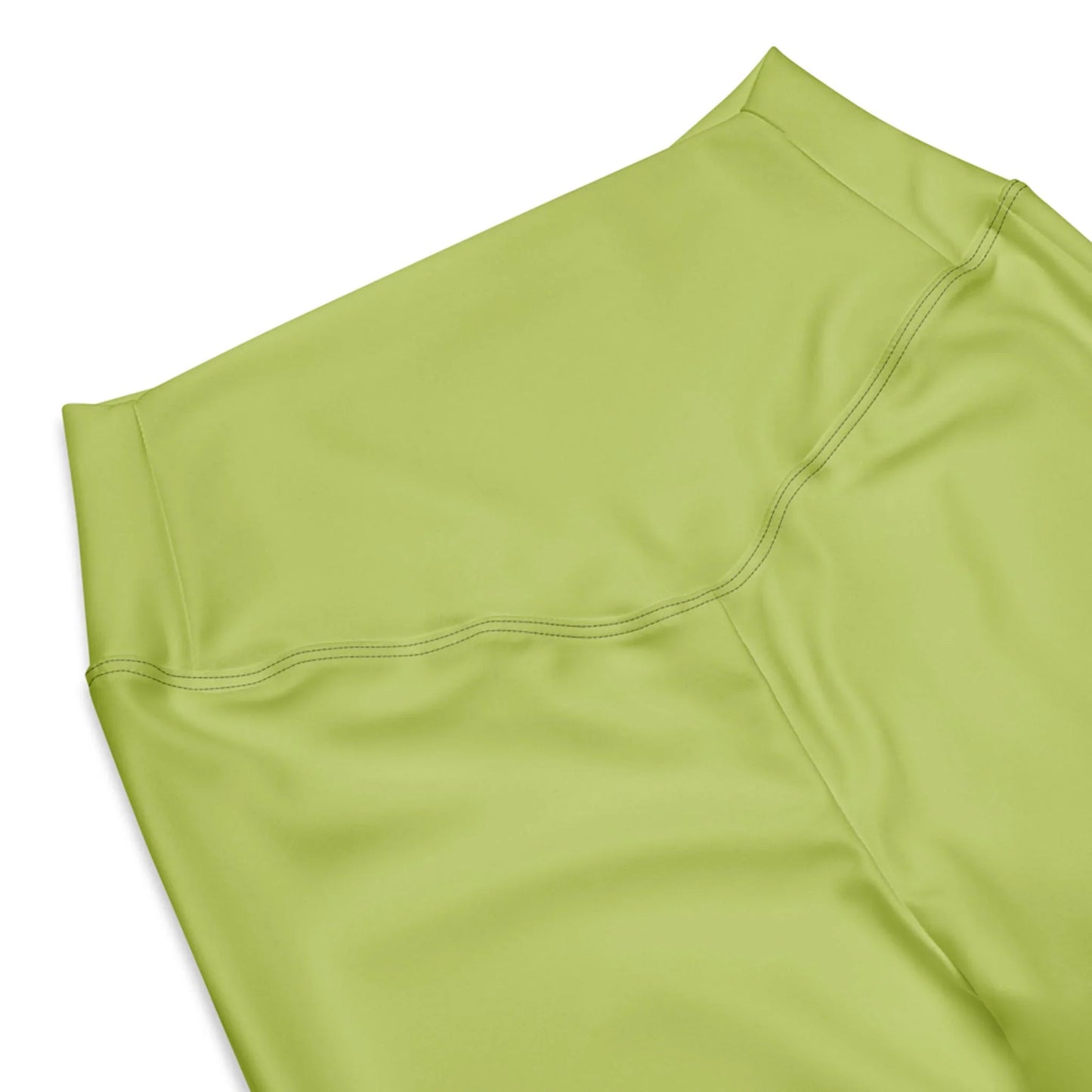 A close-up of the high waist and upper section of Printful Carolina Flared Performance Leggings for women in light green, highlighting smooth fabric and detailed stitching against a white background.