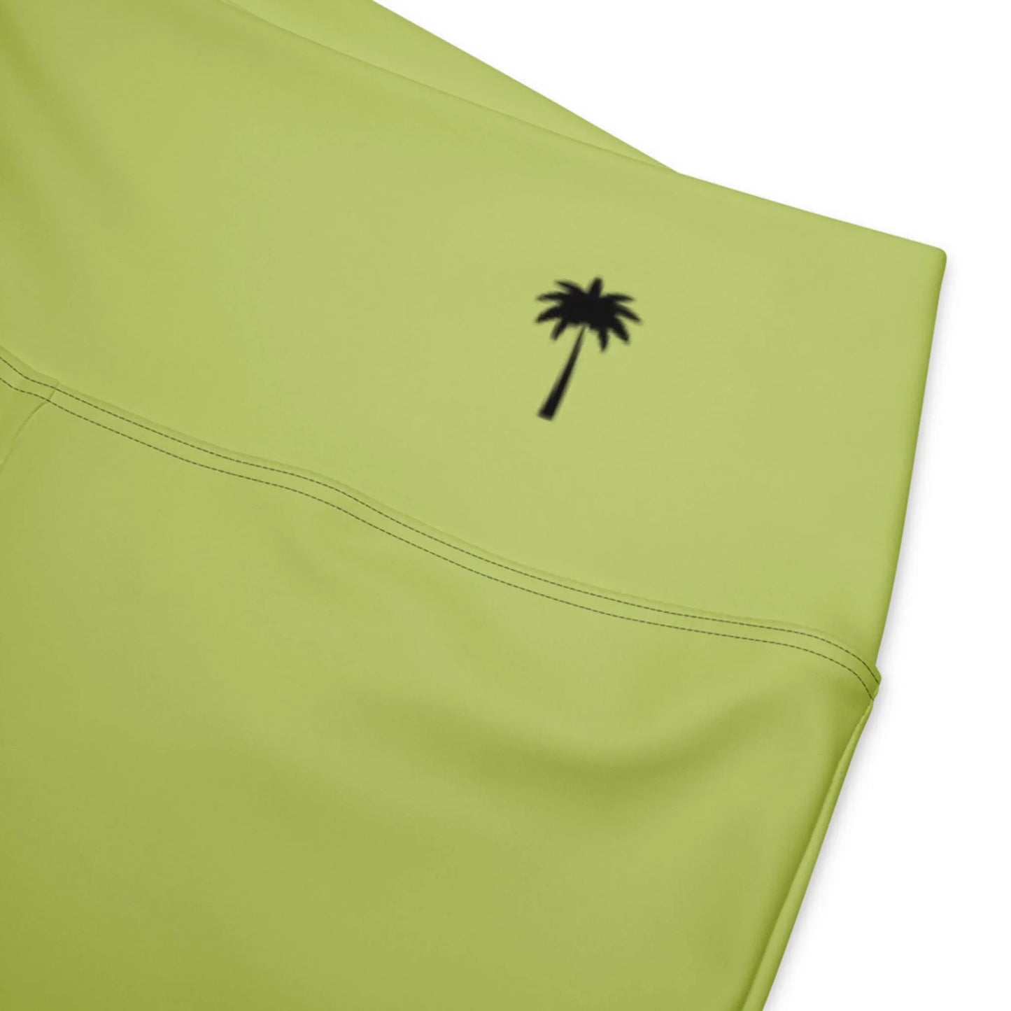 Close-up of light green Carolina Flared Performance Leggings by Printful, featuring a small black palm tree graphic near the waistband.
