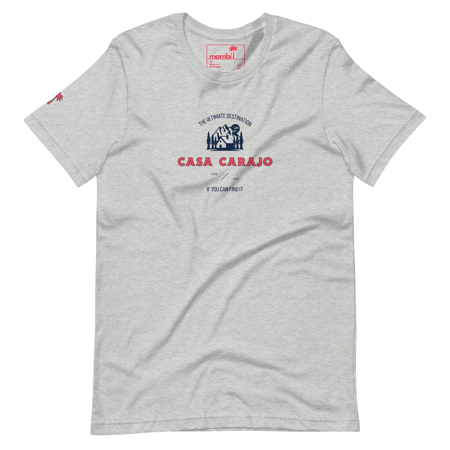 Light gray t-shirt with a blue and red graphic. Text reads: The Ultimate Destination CASA CARAJO above a cartoon-style house, adding a Mambí twist. Below, in small text: If you can find it. Red logo on left sleeve.