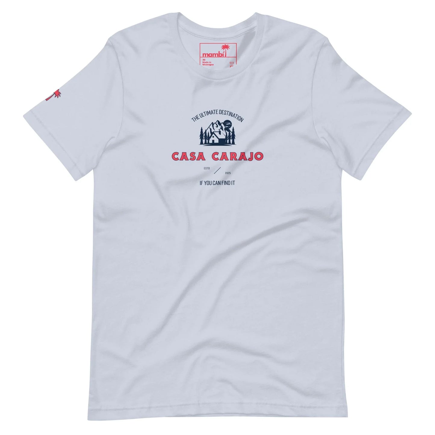 White t-shirt with a small illustration of a house and palm tree on the chest, featuring “The Ultimate Destination CASA CARAJO If you can’t find it, you can’t do it.” in blue and red. Includes a Mambí-inspired red palm icon on one sleeve.
