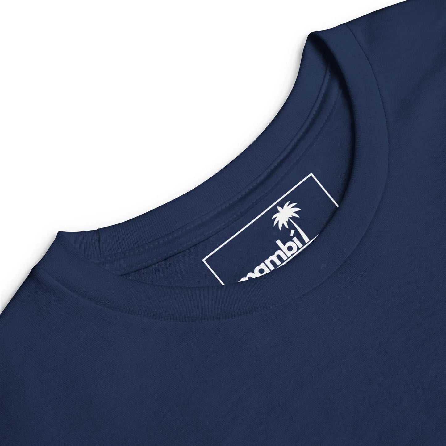 Close-up of a navy blue Mambí crew neck t-shirt, featuring the inside label with a white palm tree graphic and partial brand name on a rectangular tag.