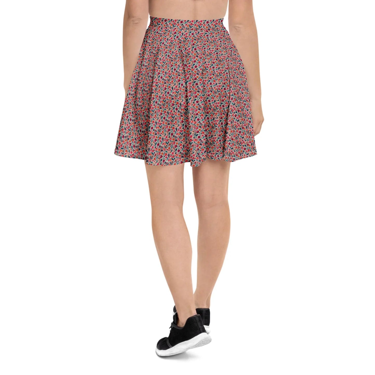 A person wearing a red and black Mambí floral-patterned flared skirt and black sneakers, seen from the back against a plain white background.