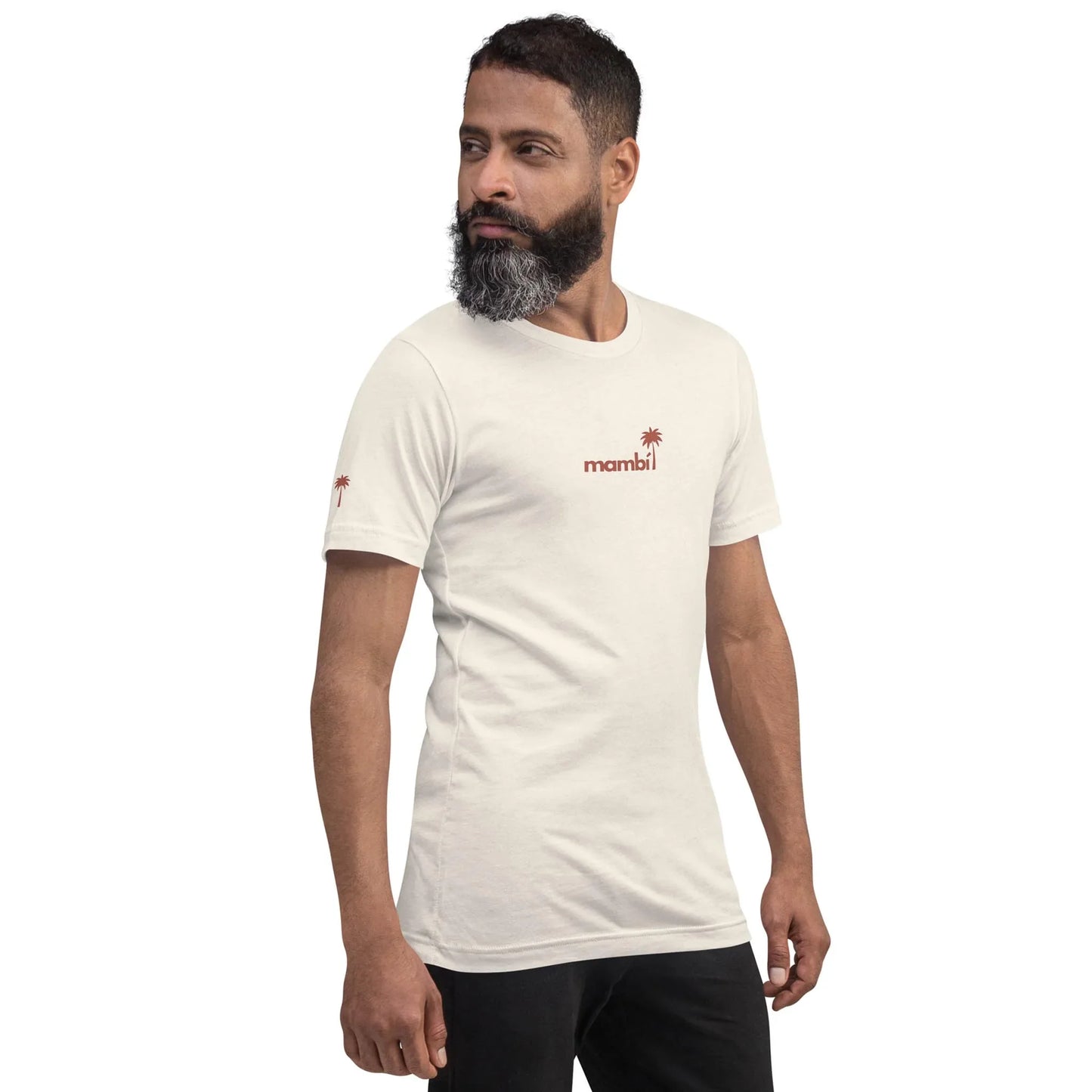 A man with a beard is wearing a white Mambí t-shirt featuring a red palm tree graphic on the chest. He stands and looks to his left against a plain white background.