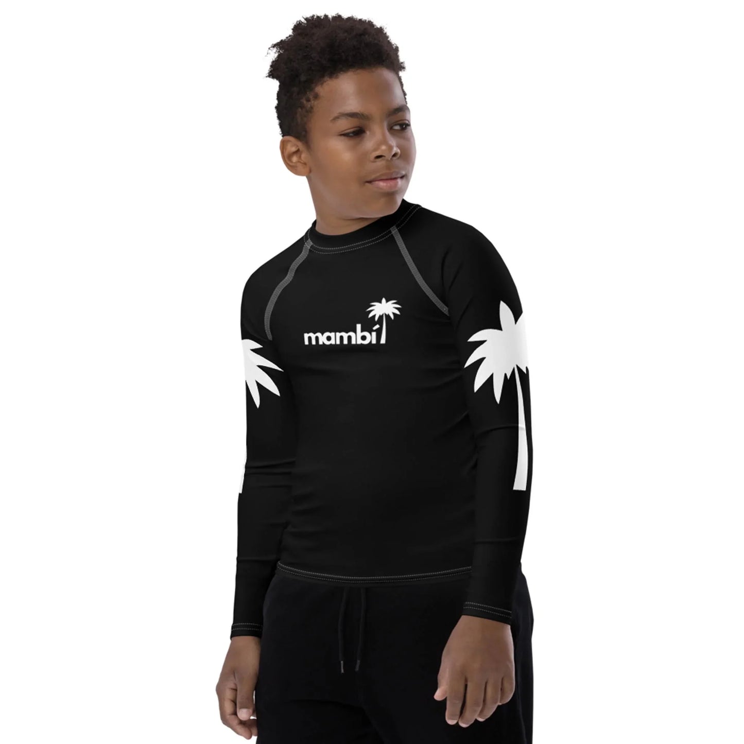 A young boy wearing a black long-sleeve rash guard with white palm tree designs on the sleeves and the word Mambí with a palm tree logo on the chest stands looking to the side against a plain background.