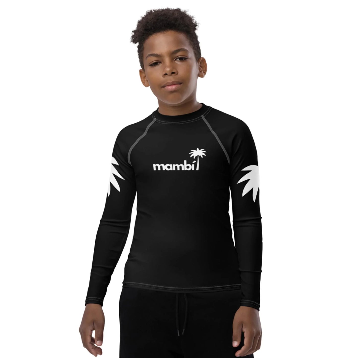 A young boy wears a black long-sleeve Mambí rash guard with white palm graphics on the sleeves and a palm tree logo on the chest, standing against a plain white background.