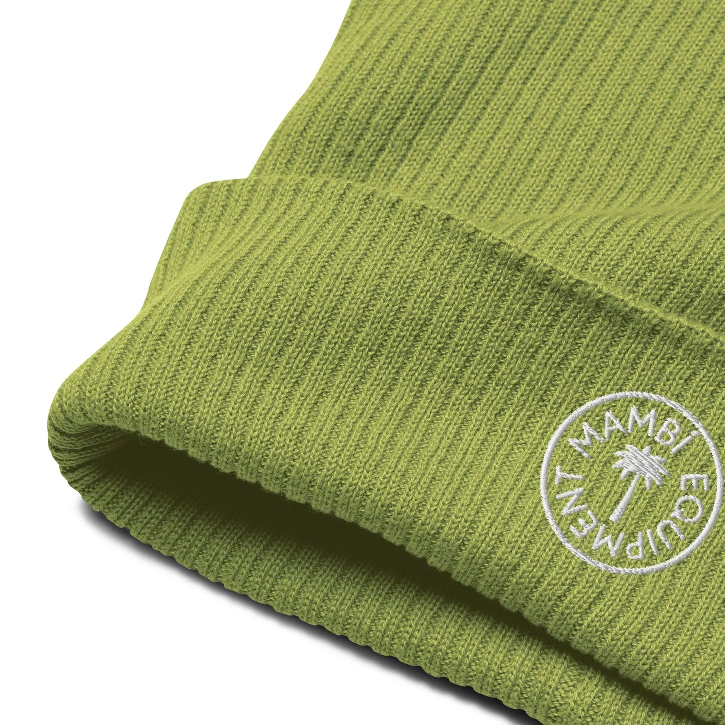 Close-up of a green ribbed knit beanie featuring a white circular embroidered patch that reads Mambí ECO FRIENDLY with a small palm tree in the center.