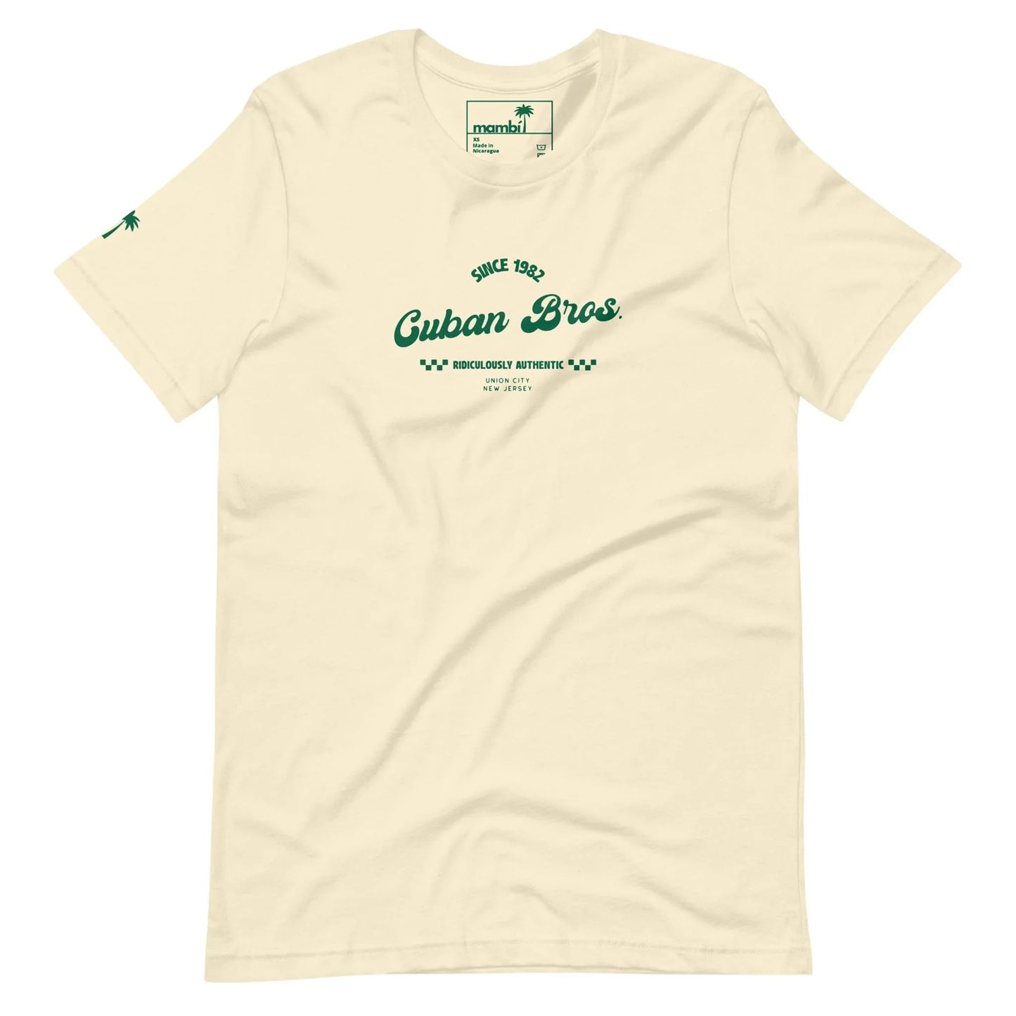 The Cuban Bros Graphic Tee | Unisex by Printful is an off-white t-shirt from the Neighborhood Collection with green Since 1982 Cuban Bros. Brooklyn’s Authentic New York text on the chest and a small palm tree logo on the left sleeve.