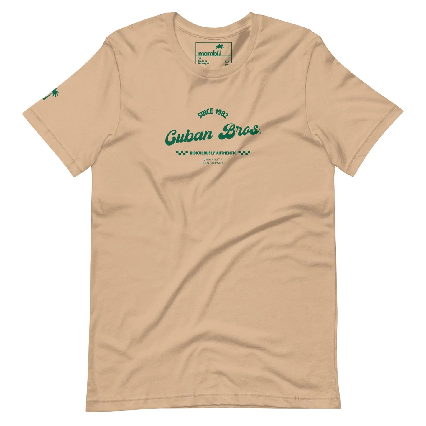 The Cuban Bros Graphic Tee | Unisex by Printful is a beige t-shirt from the Neighborhood Collection, featuring green Since 1982 Cuban Bros. Brooklyn, Artistic text on the chest, a green palm tree on the sleeve, and a green collar label.