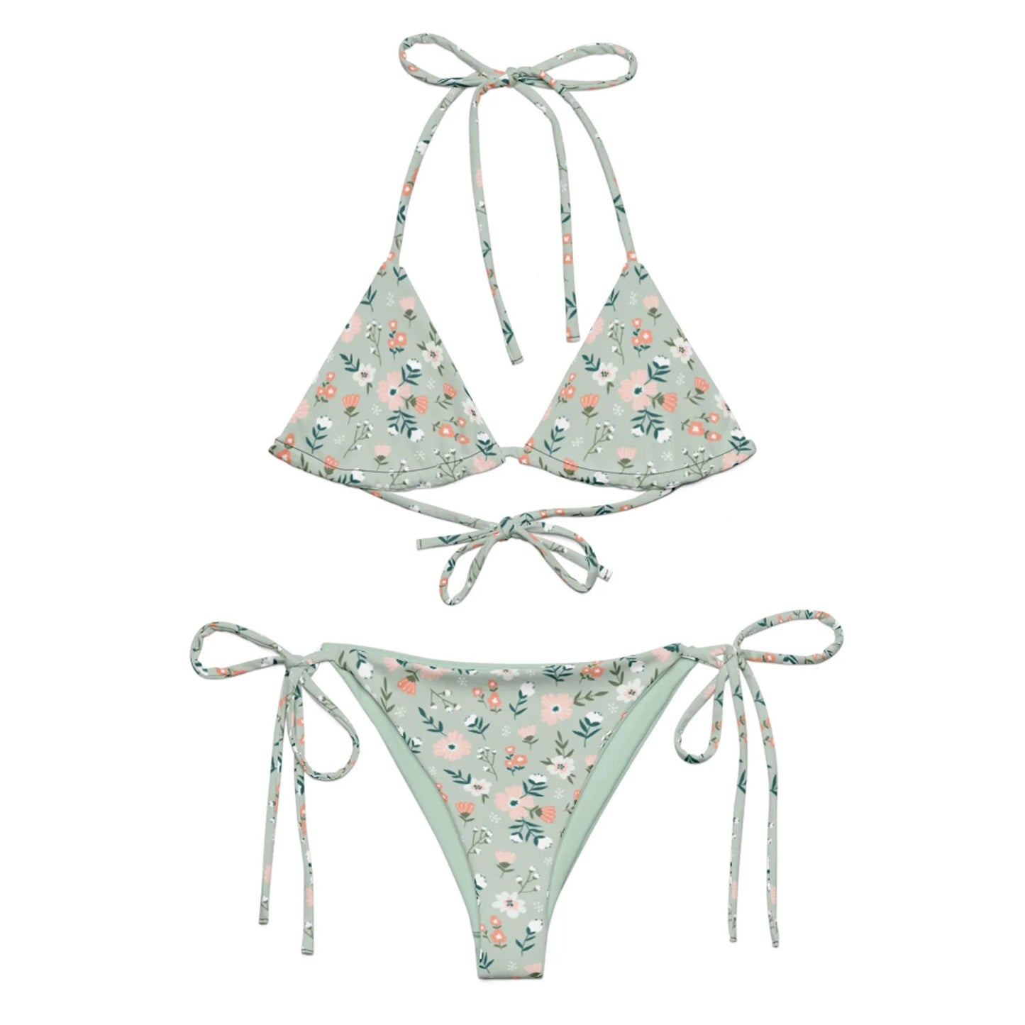 The Daniella String Bikini Swimsuit by Printful features a light green floral print with pink and white flowers, is made from recycled polyester with UPF 50+, and has a triangle top with neck/back ties and adjustable side-tie bottoms.