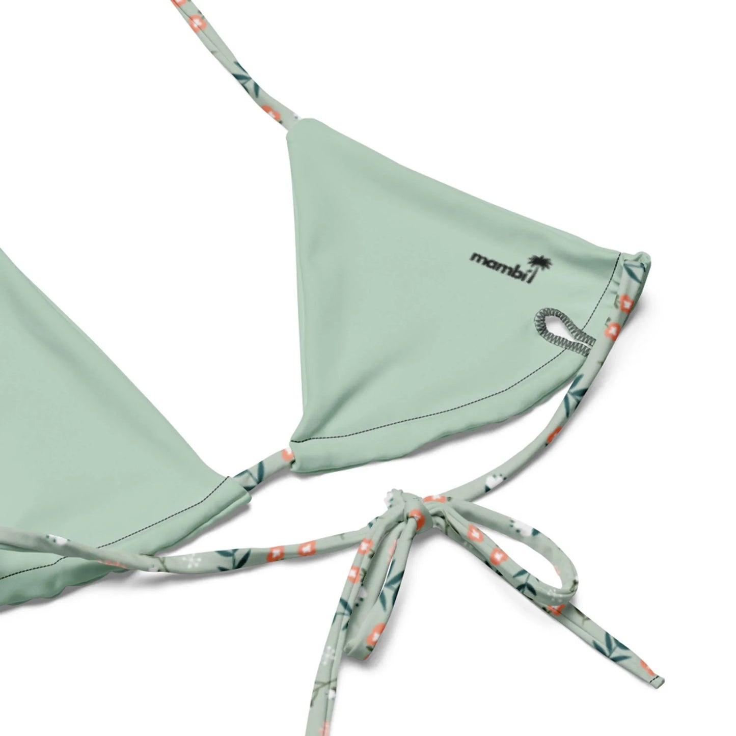 Close-up of the Printful Daniella String Bikini Swimsuit for women, featuring light green recycled polyester, patterned straps, a palm tree graphic, small mombai logo, and UPF 50+ protection on one triangle cup.
