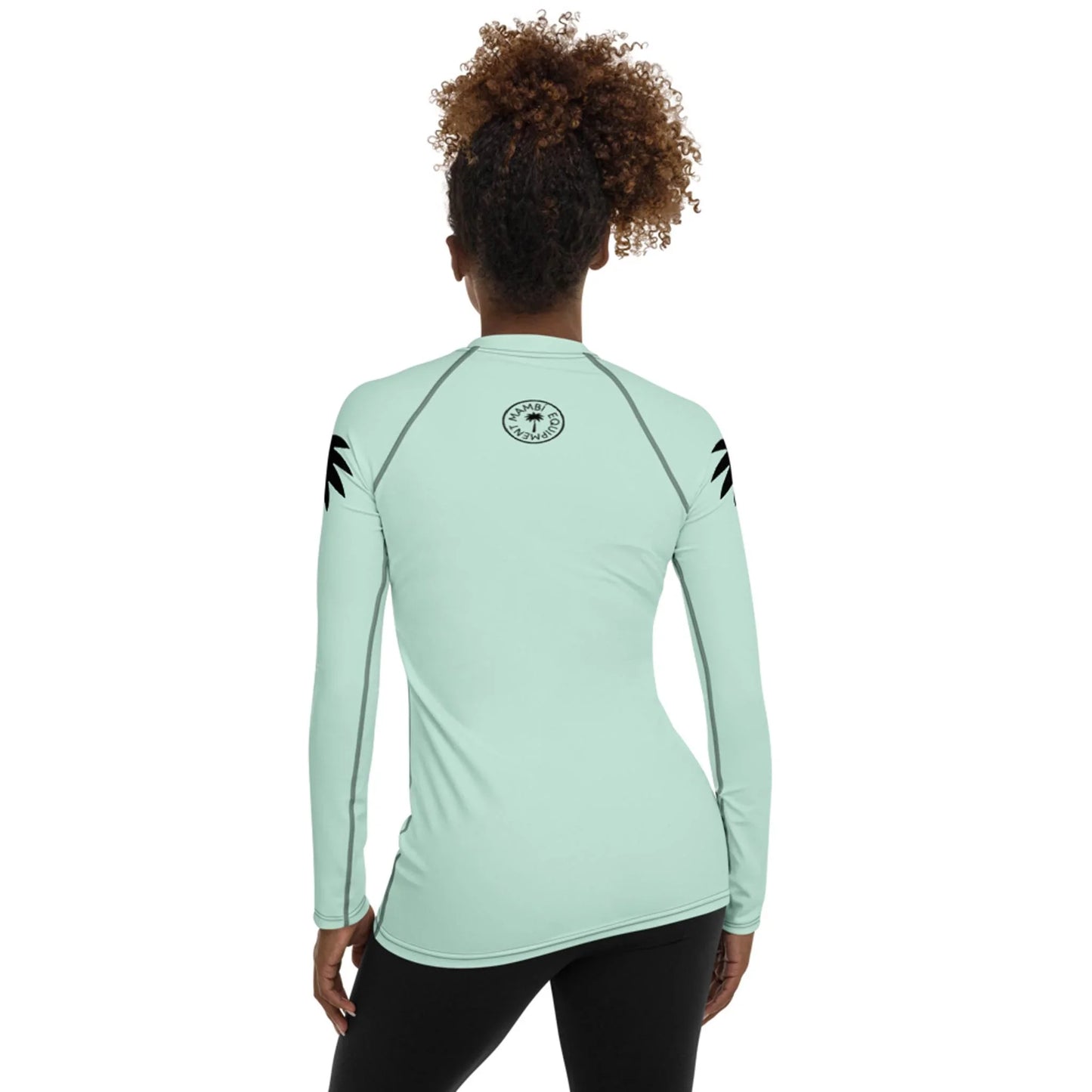 A woman with curly hair models the Printful Ellie Classic Long-Sleeve Rash Guard for women in light blue, featuring black upper sleeve designs and a circular back logo, standing with her back to the camera against a white background.