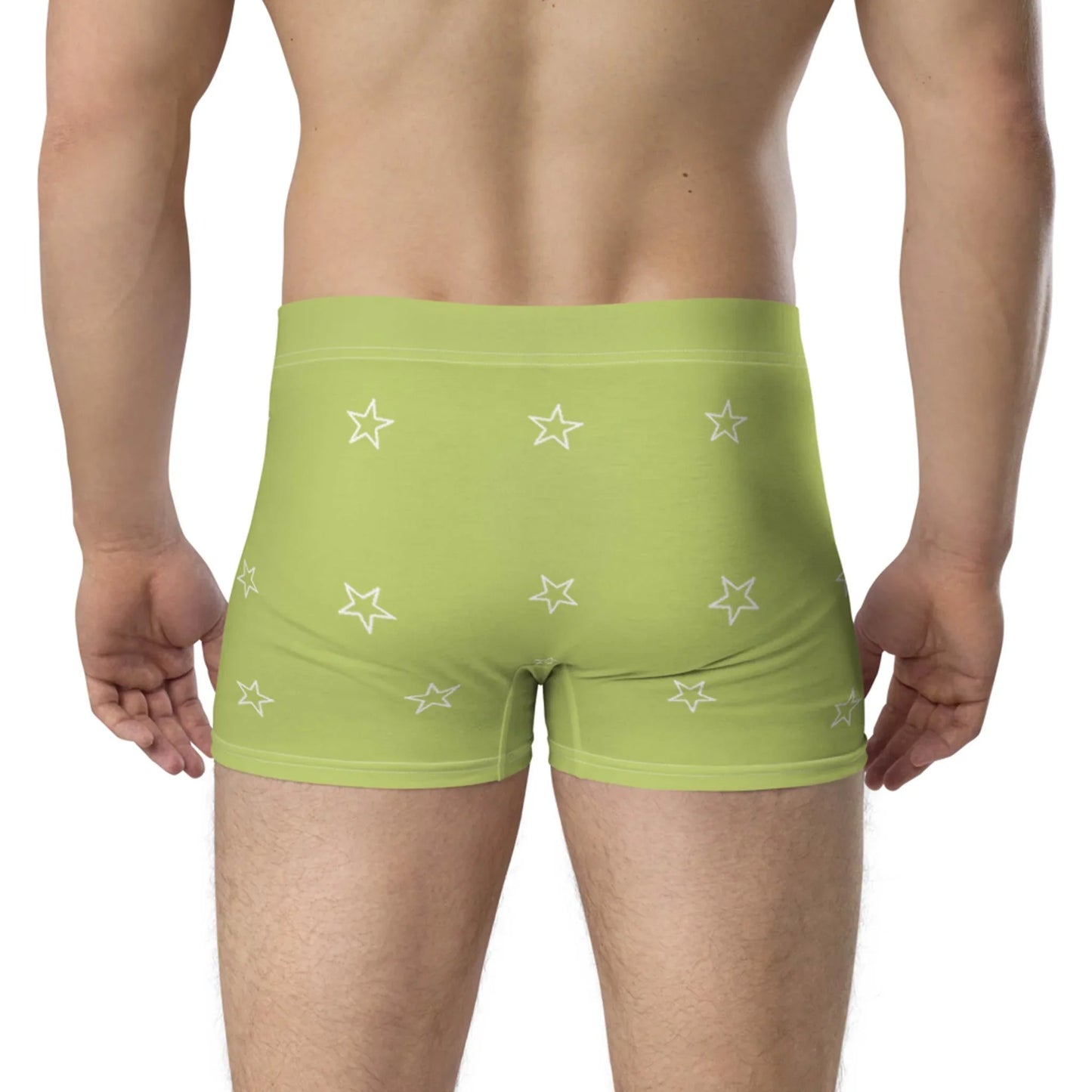 A person is shown from the waist down, wearing light green Mambí boxer briefs with a pattern of white stars. They are standing with their back to the camera against a plain white background.
