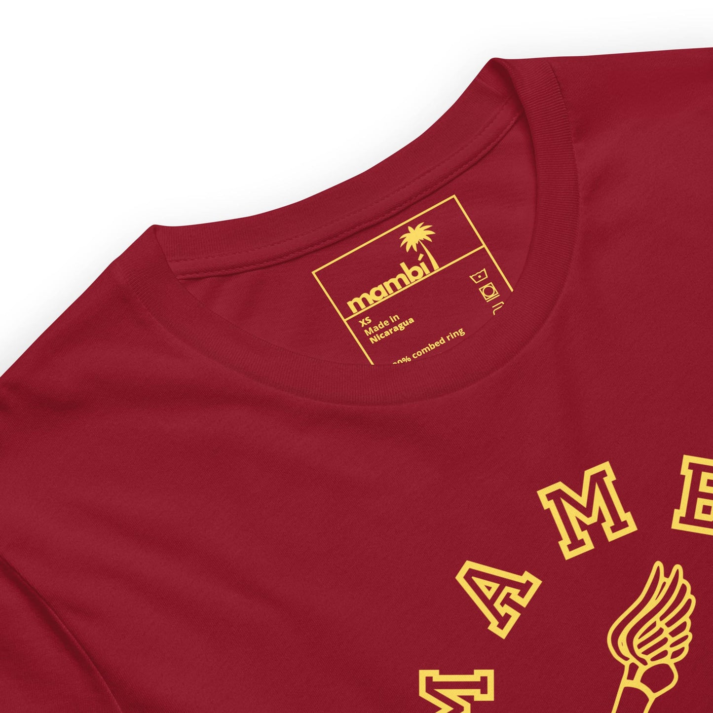 Close-up of a red t-shirt with yellow graphic and text. The inside label reads Mambí, featuring a palm tree icon and sizing details. Part of the yellow design is visible on the front of the shirt.
