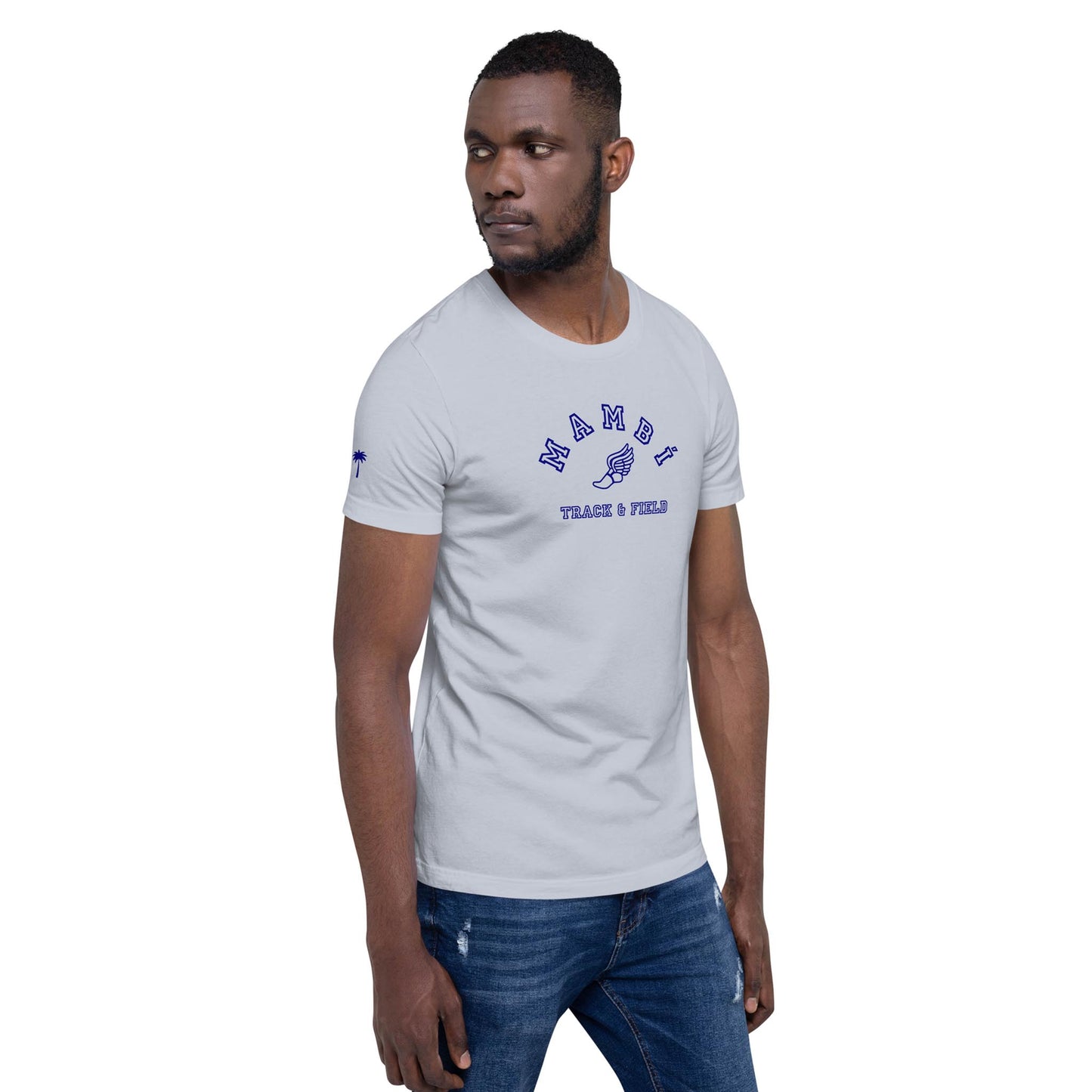 A man wearing a light gray t-shirt with NAMBU PEACE x FIELD and a Mambí vibe stands sideways, looking to his left, right arm relaxed and left hand in his pocket, against a white background.