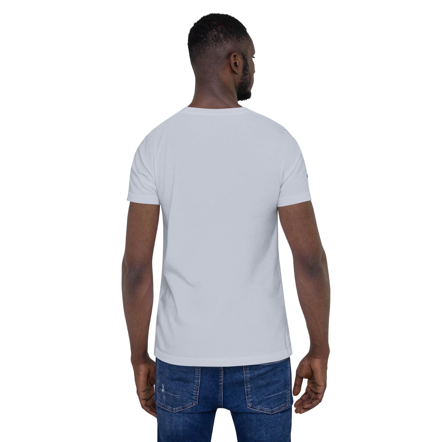 A man is standing with his back to the camera, wearing a plain light gray short-sleeve Mambí t-shirt and blue jeans against a white background.