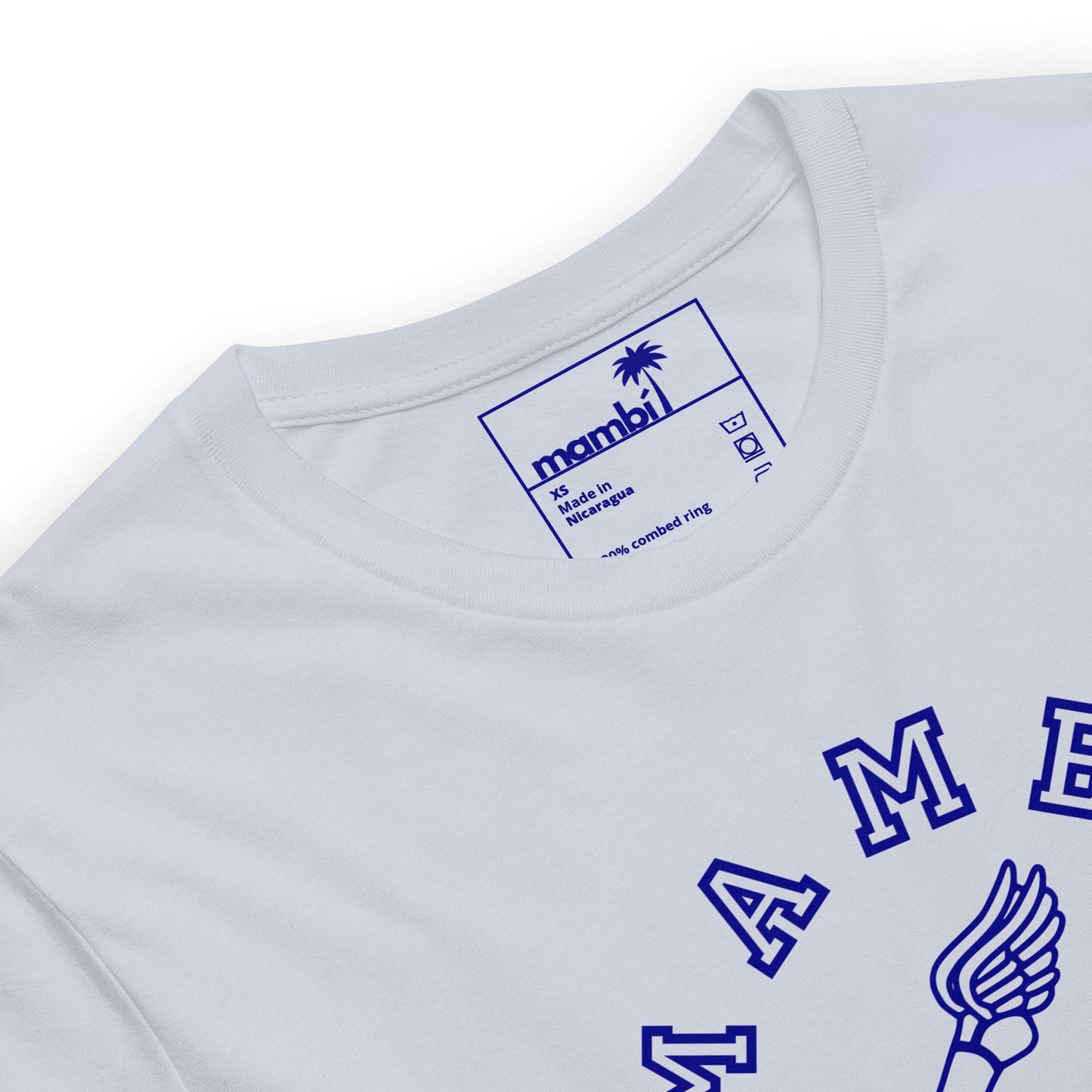 Close-up of a white t-shirt with a blue printed label inside the neck reading Mambí, size M, and Made in Nicaragua. Part of a blue winged logo and lettering are visible on the front.