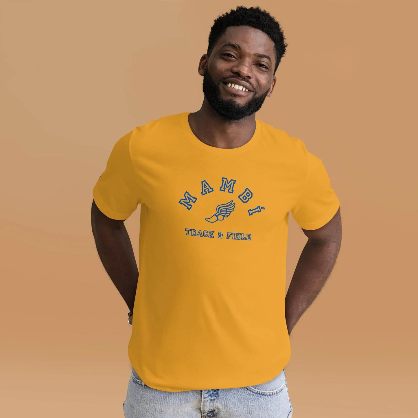 A smiling man wears the Printful Falcon Varsity Track & Field Tee in royal print, hands behind his back against a beige background, pairing this unisex throwback style with modern comfort in light blue jeans.
