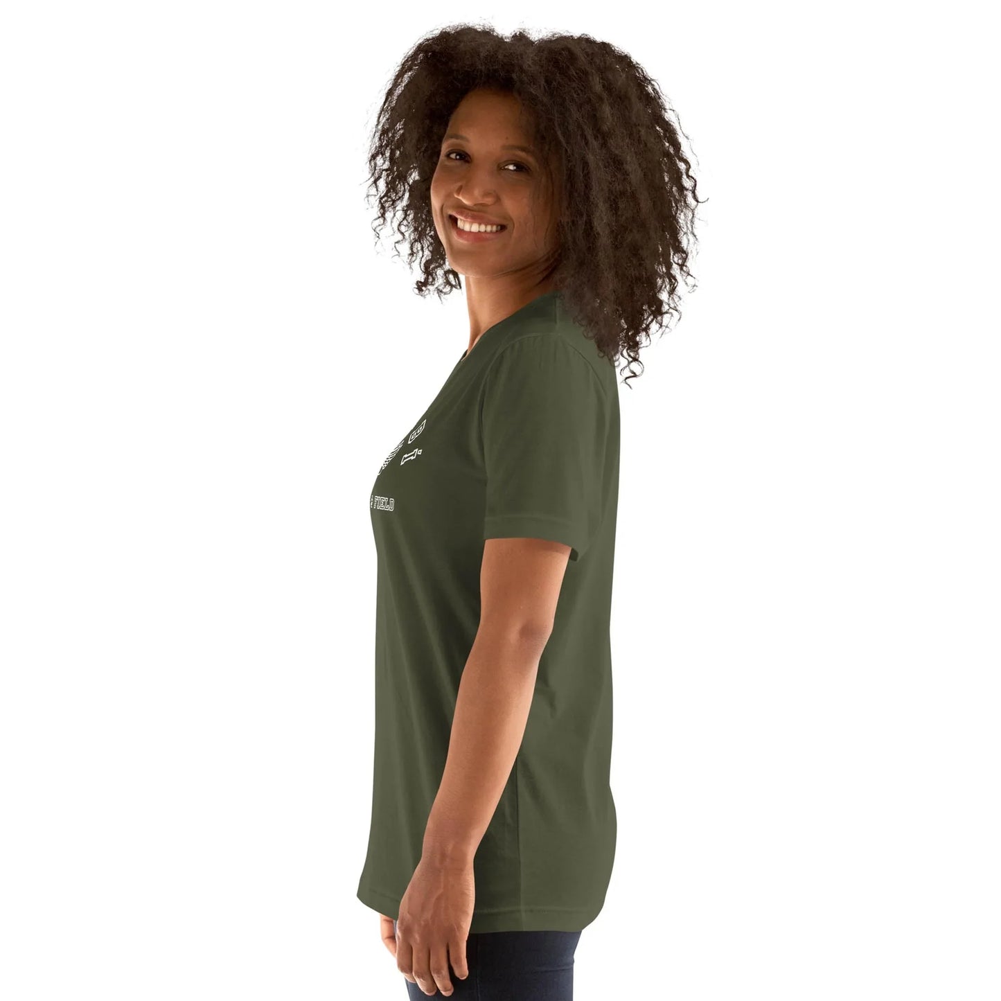 Woman with curly hair smiling and standing sideways, wearing a dark green Mambí t-shirt and dark pants against a plain white background.