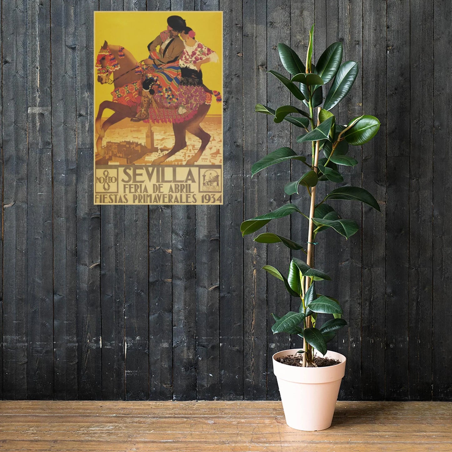 A tall potted plant stands on a wooden floor against a dark wood wall. Above it, a colorful vintage Mambí poster with Spanish text shows a rider on horseback and the city of Seville in the background.
