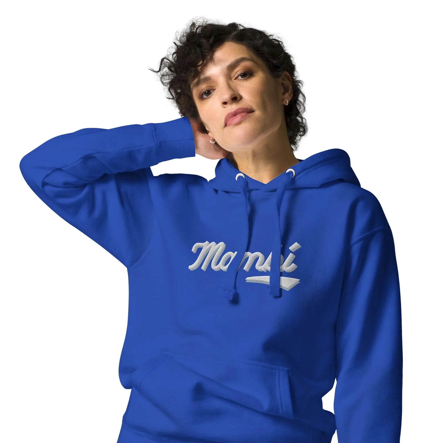 Person with short curly hair wearing a bright blue hoodie that says Mambí in white script, posing with one hand behind their head against a plain white background.
