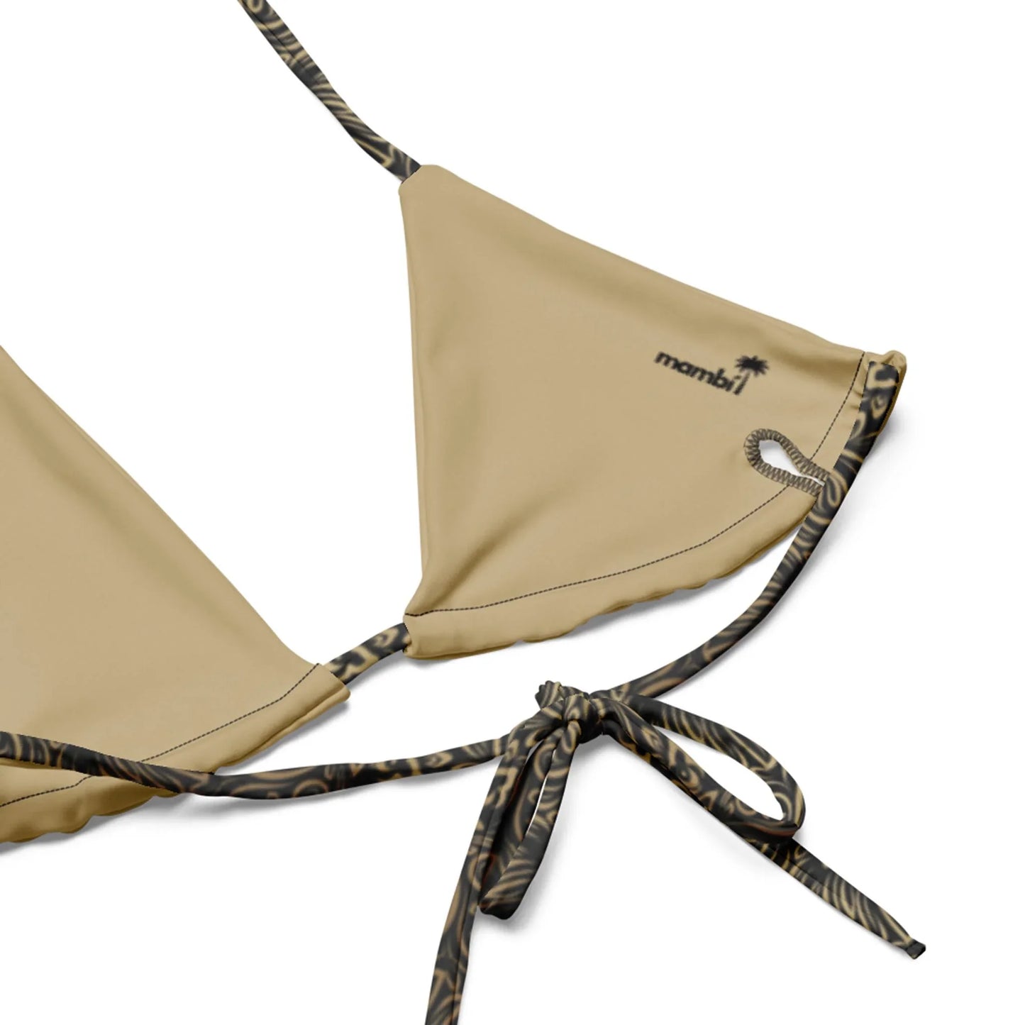 Close-up of the Flavia String Bikini Swimsuit by Printful, featuring tan recycled polyester, black and brown animal print straps, a “mambi” logo, and a small palm tree graphic.
