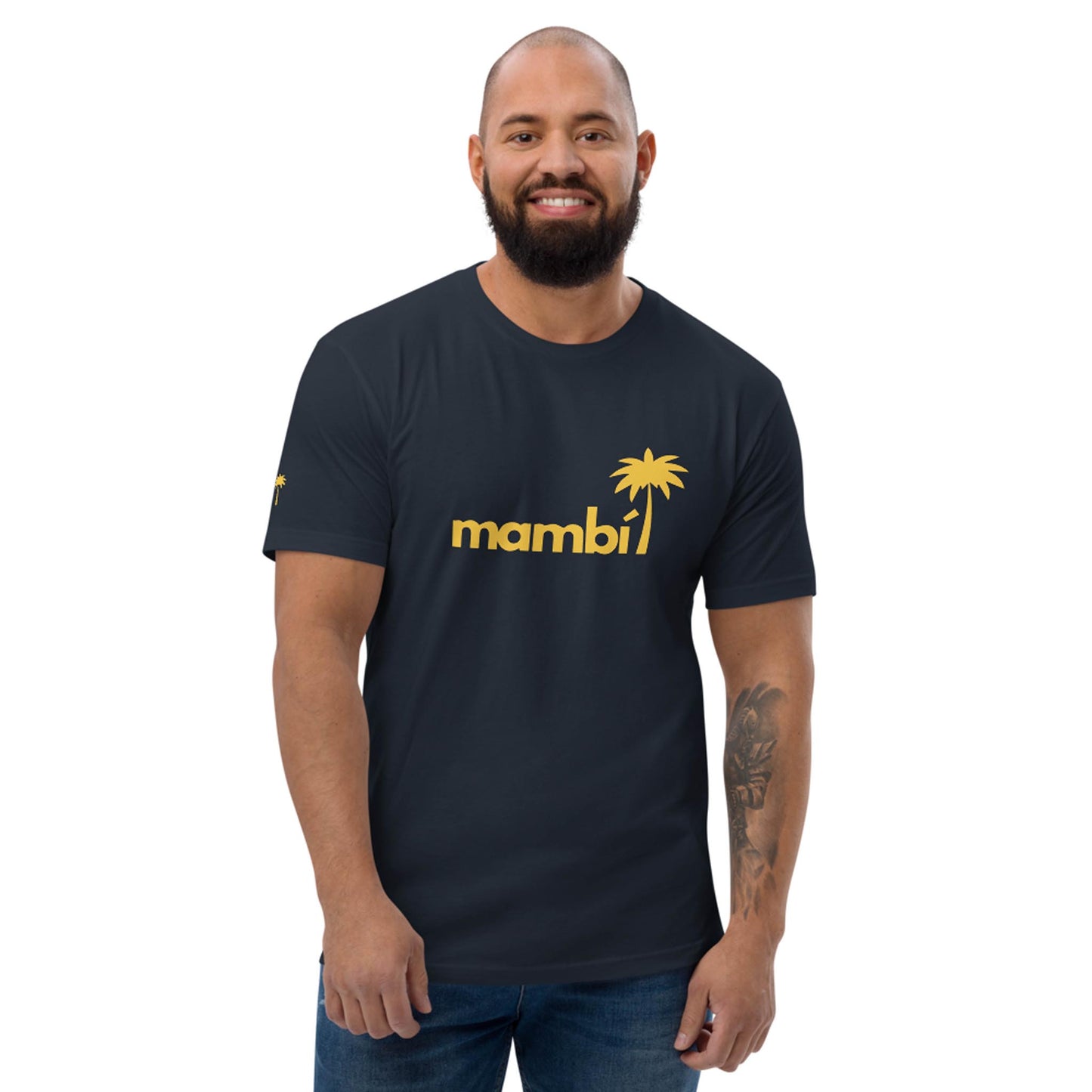 A smiling man with a beard wears a dark t-shirt featuring the yellow word Mambí and a palm tree graphic. He stands against a plain white background.