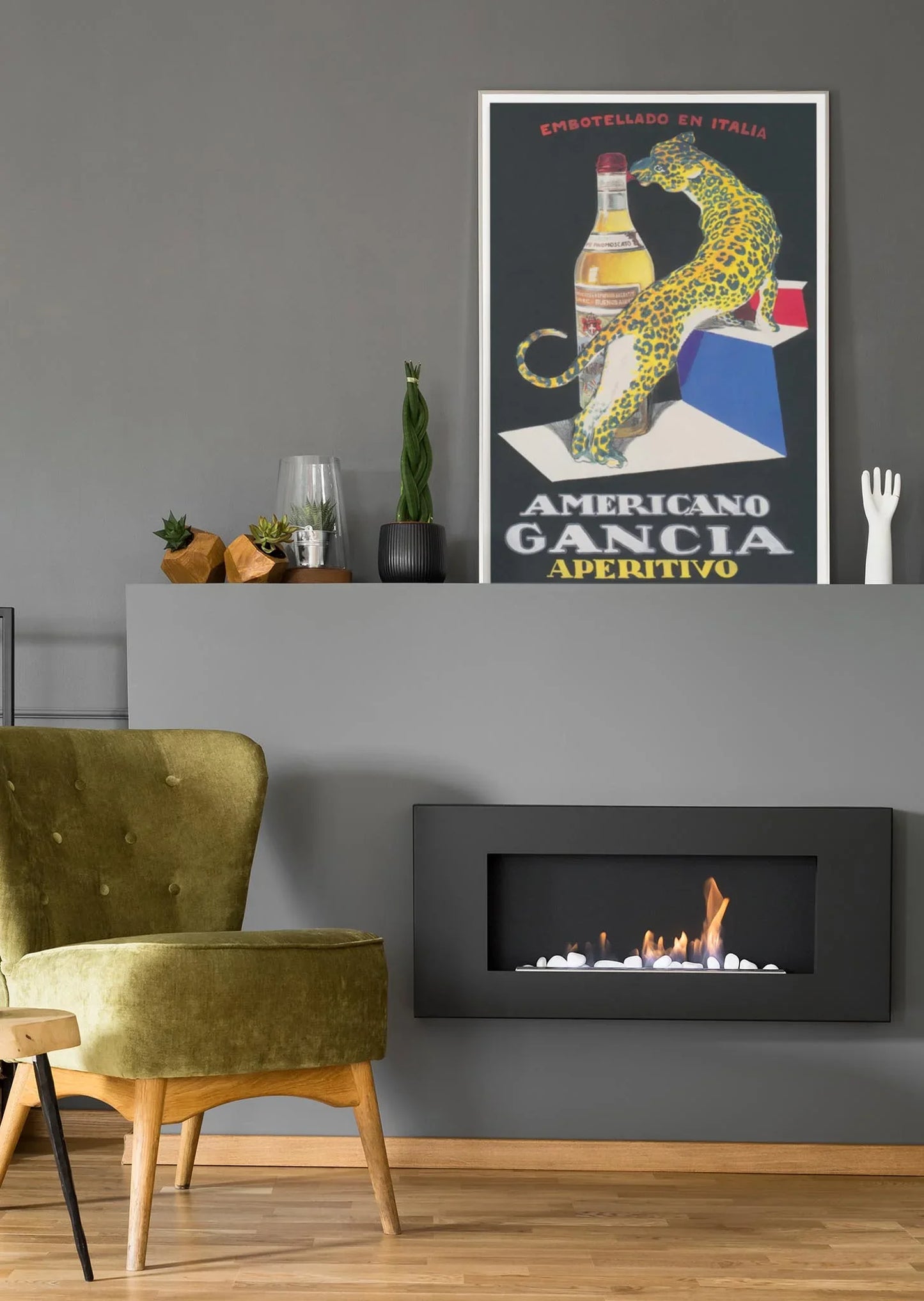 A modern living room with a green velvet chair, wall-mounted black fireplace, decorative plants, and a vintage “Americano Gancia Aperitivo” poster on a gray wall adds Mambí flair to the space.