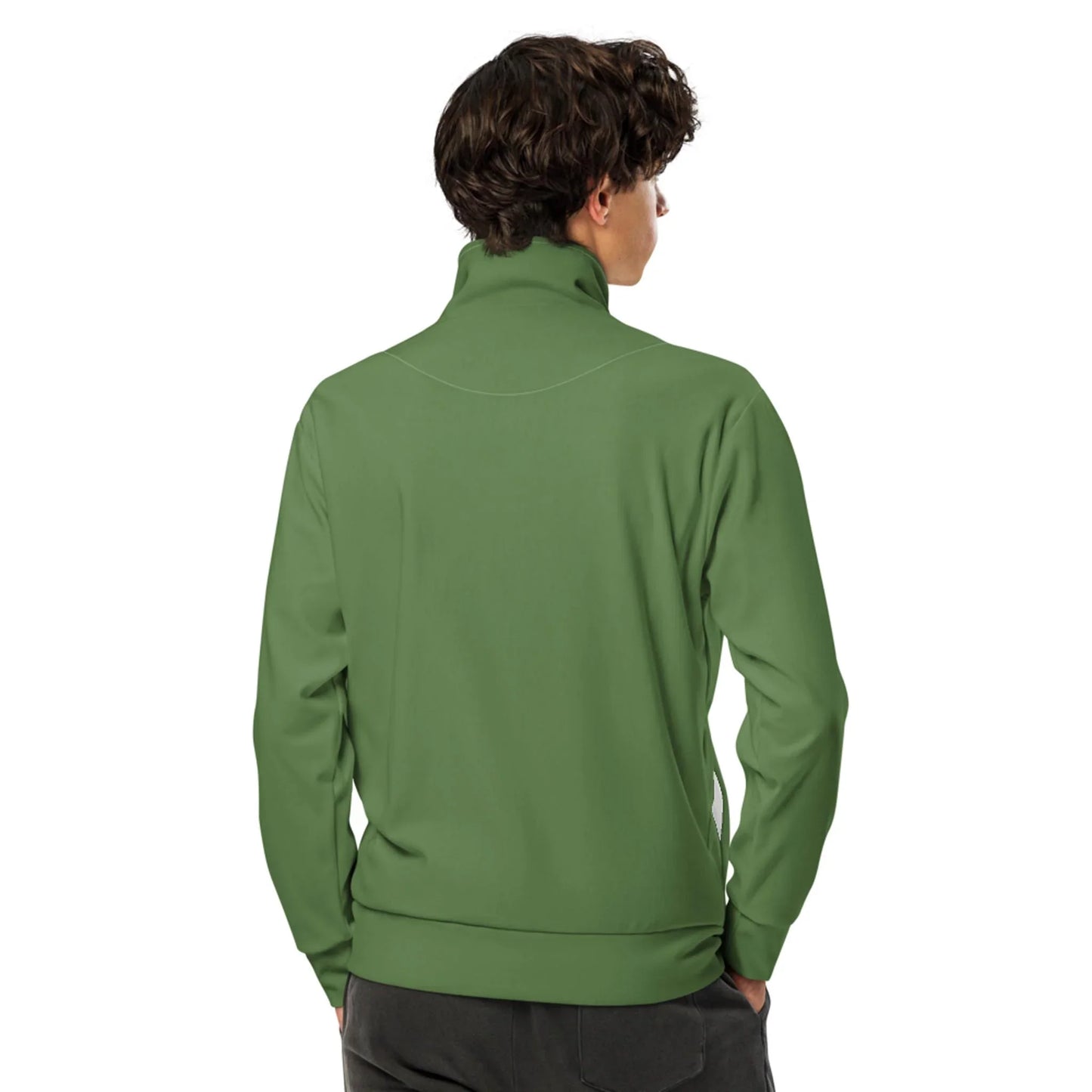 A person with curly brown hair, dressed in a light green Mambí zip-up jacket and dark pants, stands facing away against a plain white background.