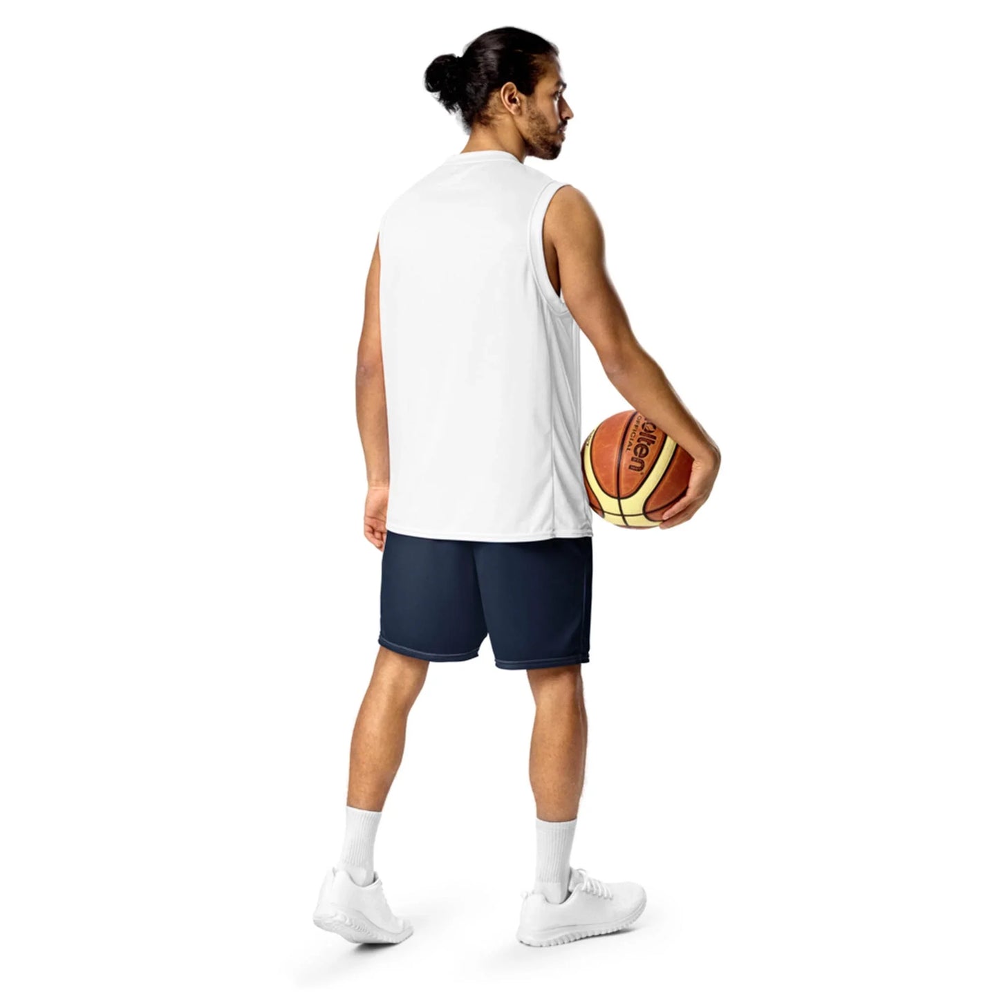 A man with long hair in a bun, wearing a sleeveless white shirt, navy shorts, white socks, and white sneakers, stands holding a basketball in his right hand against a plain white background, capturing the spirit of a modern Mambí.