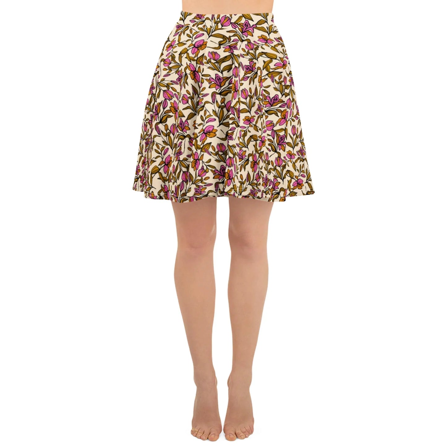 A person wearing a knee-length, pleated skirt with a colorful Mambí floral pattern on a white background stands barefoot against a plain white backdrop.